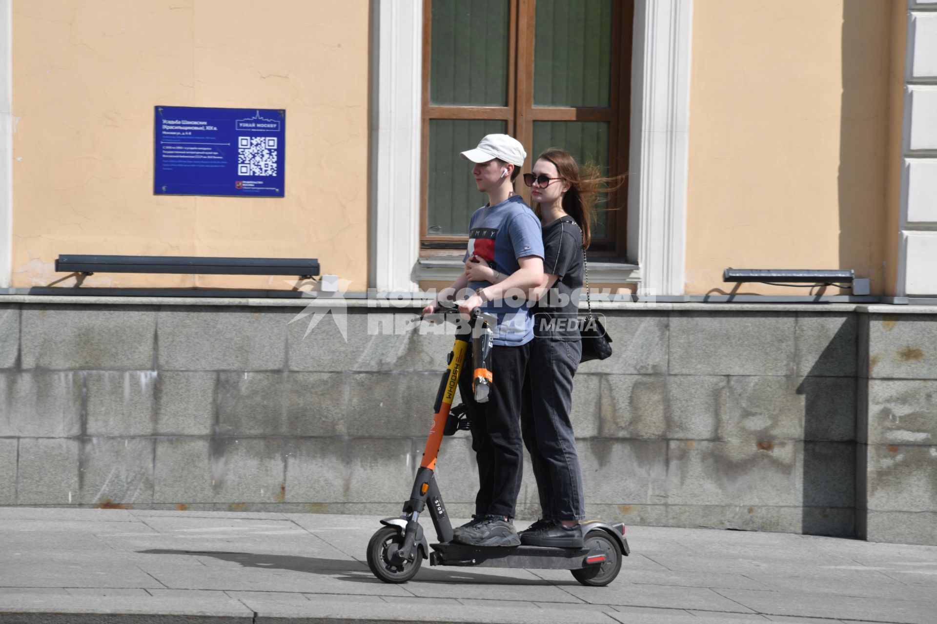 Москва.  Молодые люди едут на самокате.