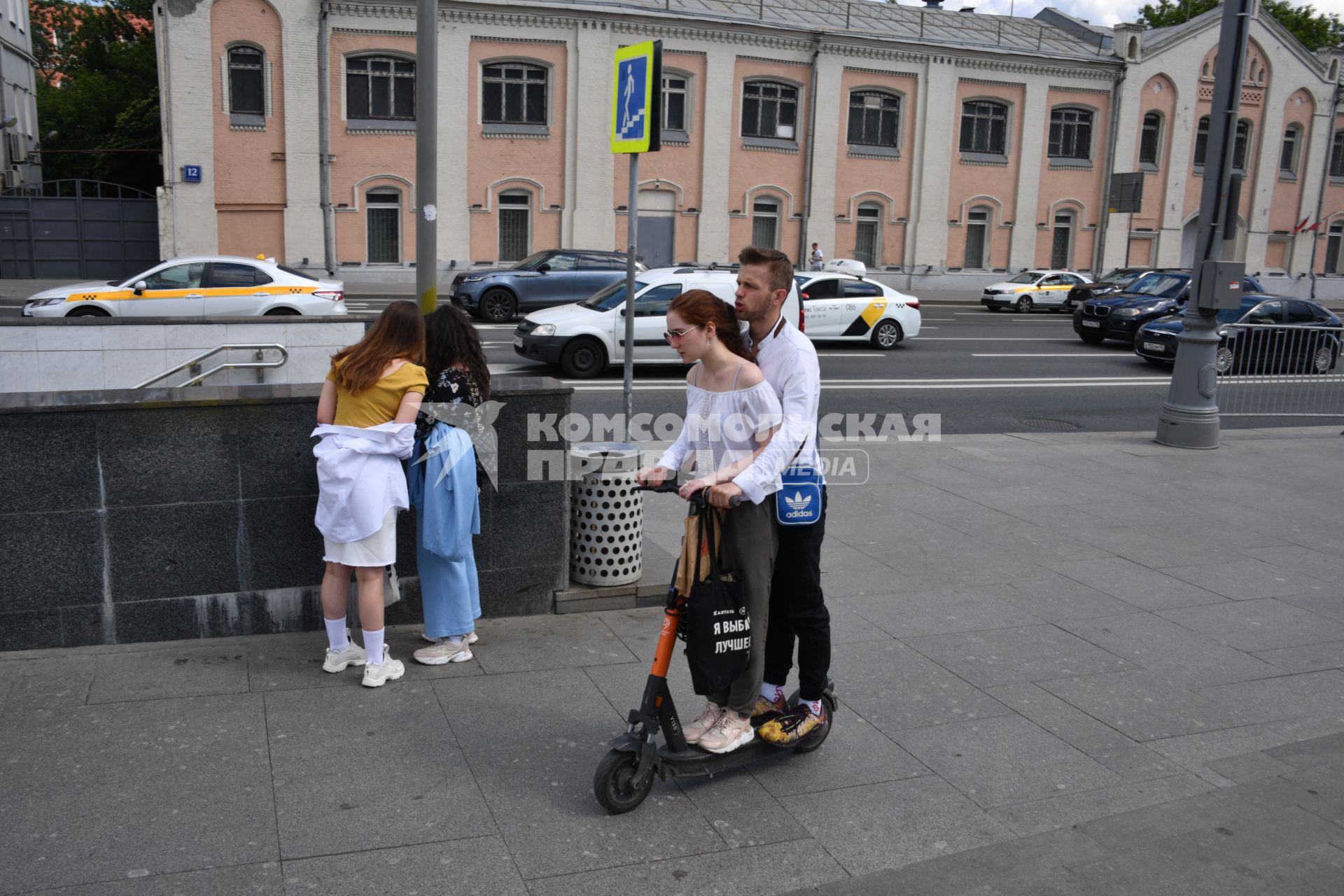 Москва.  Молодые люди едут на самокате.