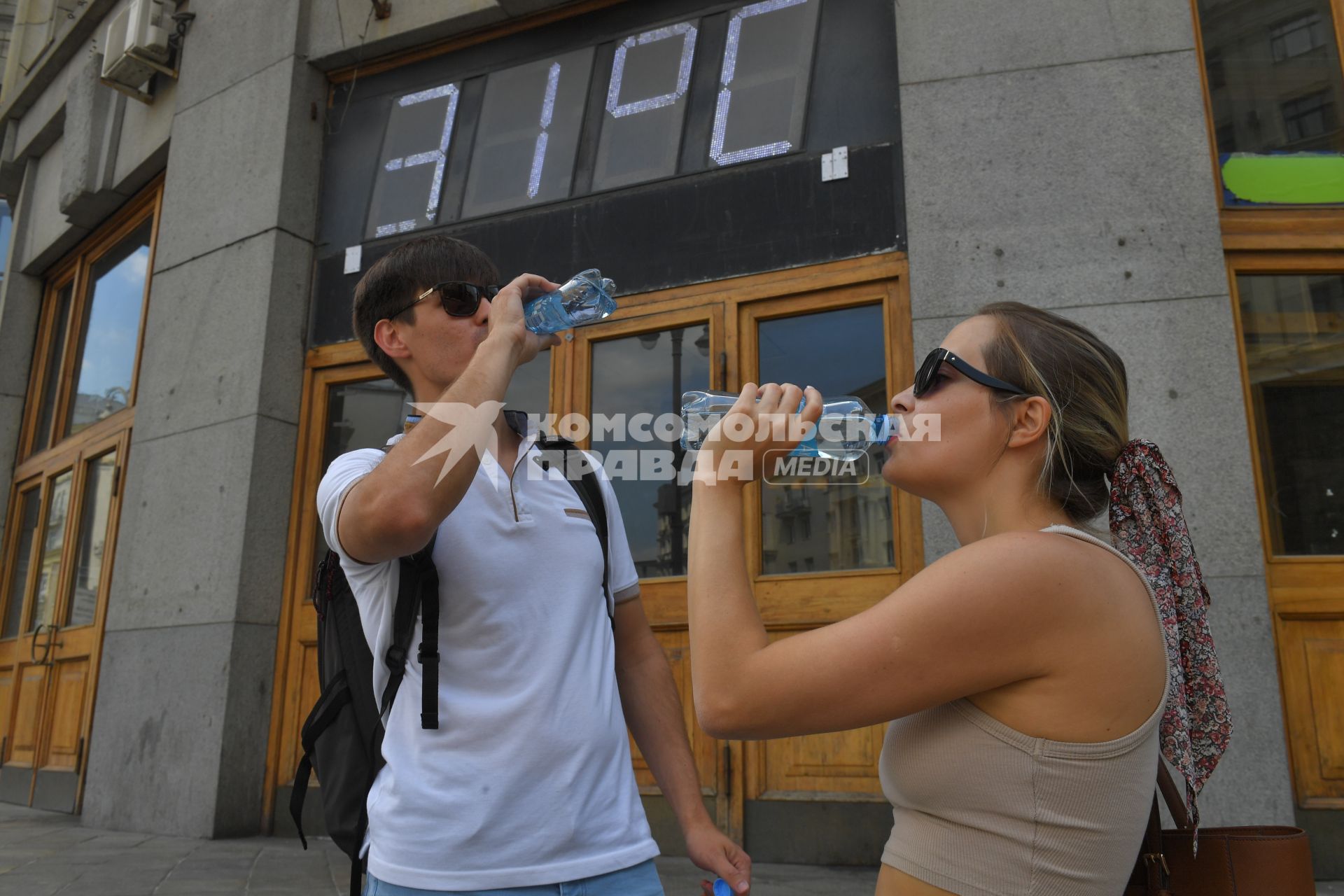 Москва. Молодые люди пьют минеральную воду на фоне градусника Центрального Телеграфа, показывающего температуру воздуха 31.