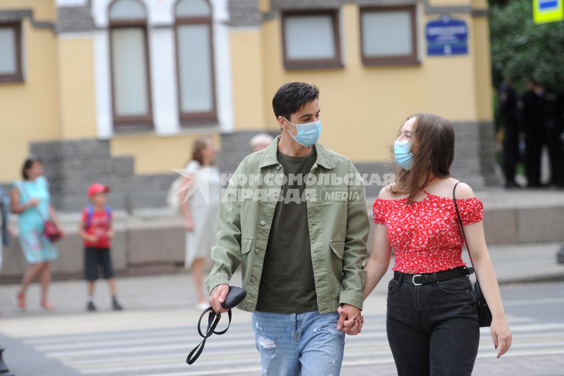 Санкт-Петербург. Парень с девушкой в защитных масках идут по пешеходному переходу взявшись за руки.