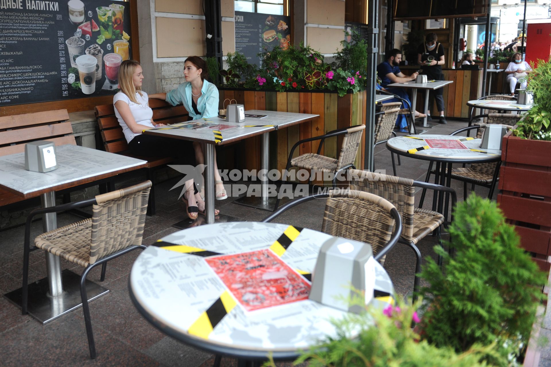 Санкт-Петербург. Посетители сидят на веранде кафе. На столиках наклеена оградительная лента.