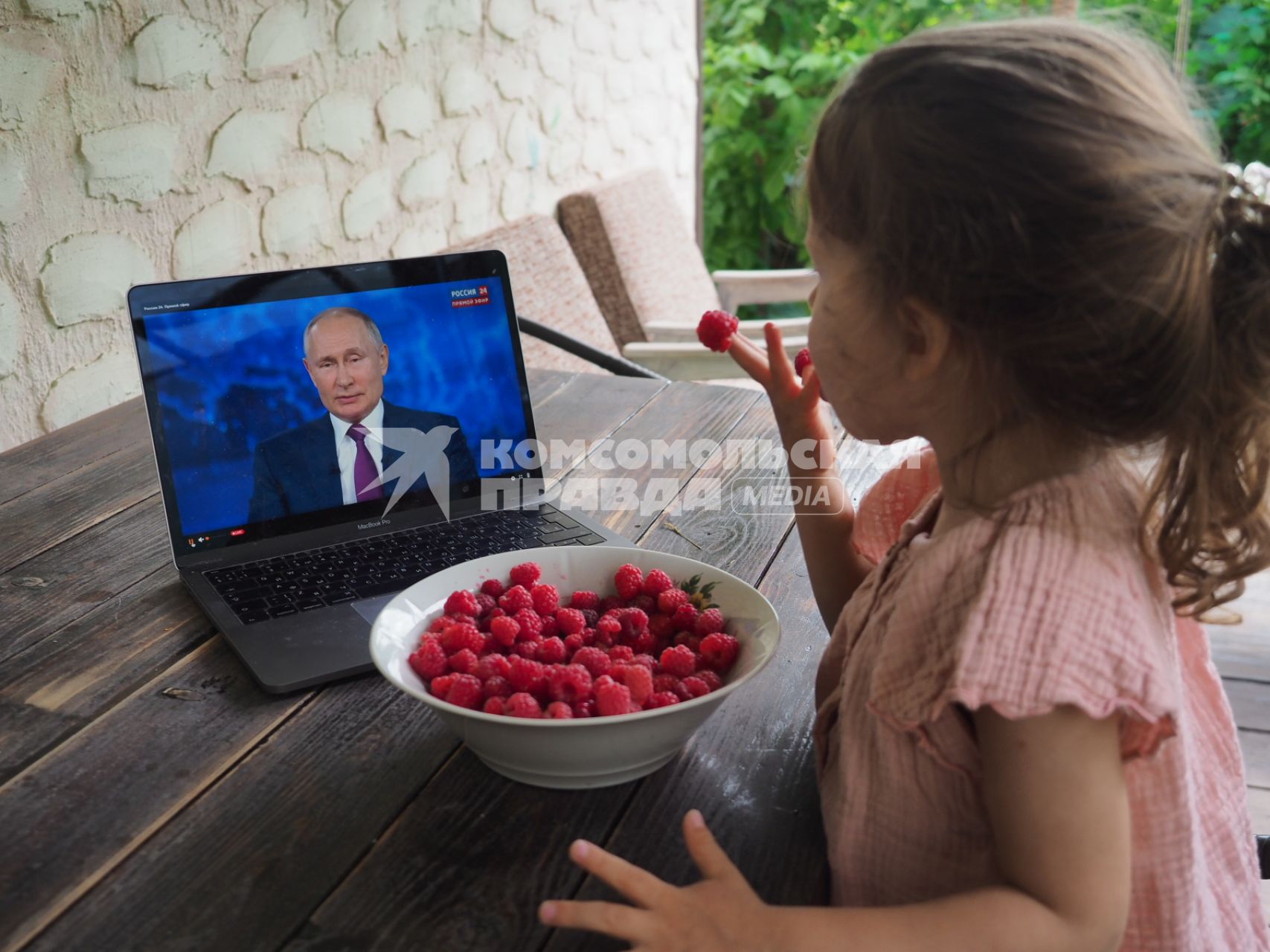 Московская область. Девочка ест малину и смотрит трансляцию прямой линии с президентом РФ Владимиром Путиным на экране ноутбука.