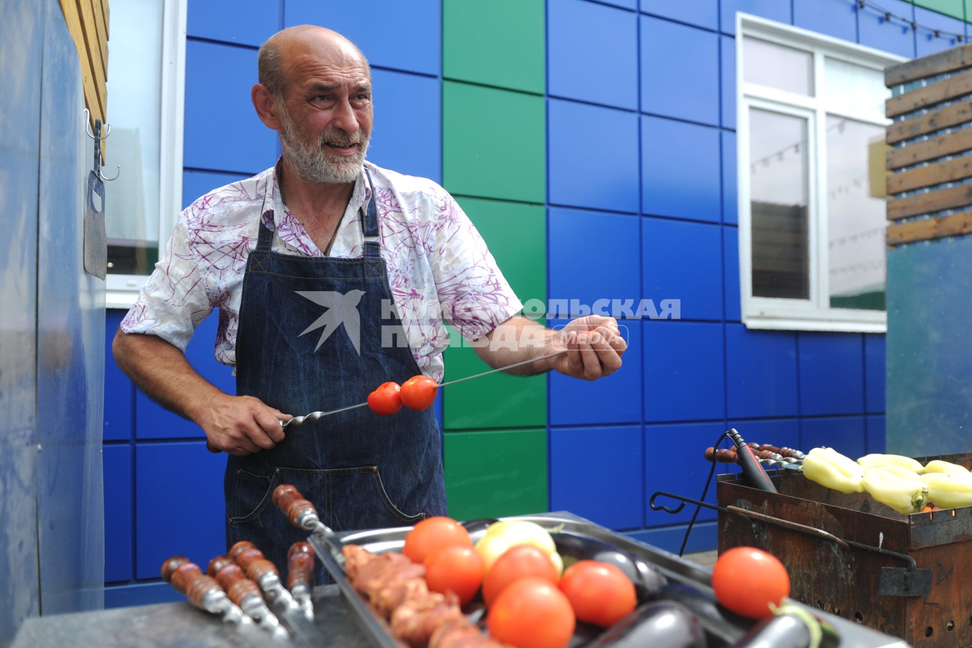 Санкт-Петербург. Шашлычник нанизывает помидоры на шампур на Южном рынке.