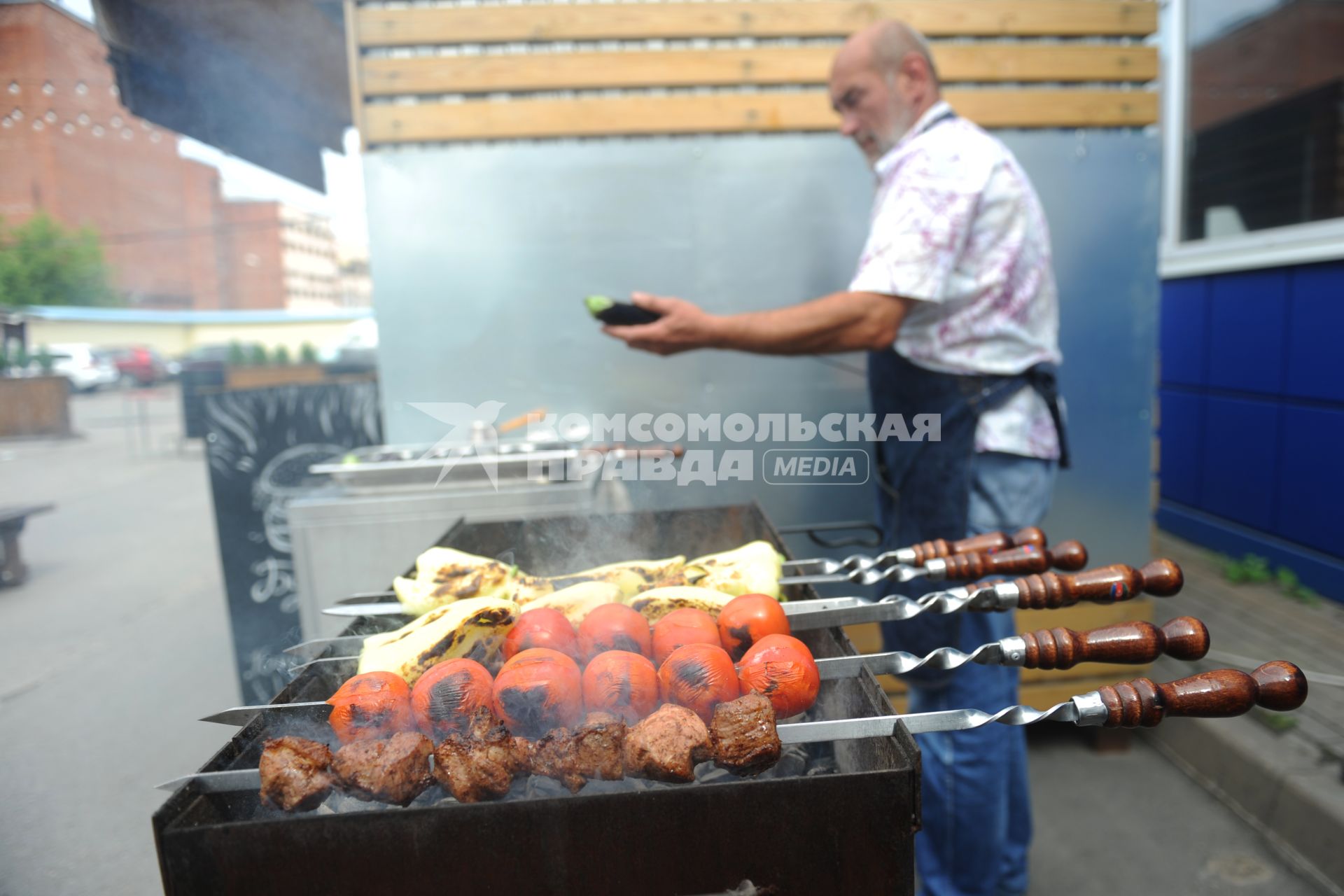 Санкт-Петербург. Южный рынок. Шашлычник жарит мясо и овощи на мангале.