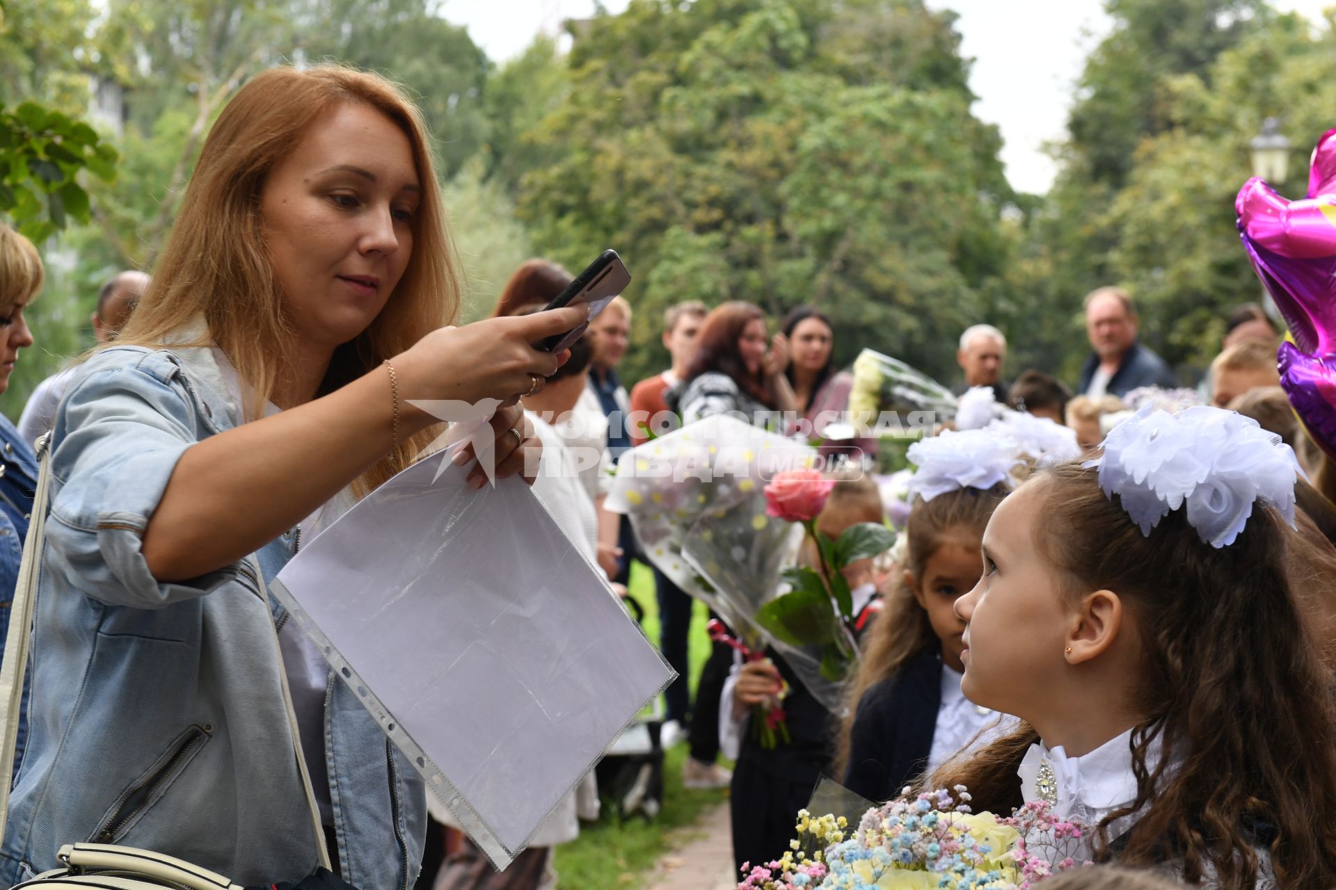 Москва. Первое сентября. Мама фотографирует первоклассницу на торжественной линейке у школы.