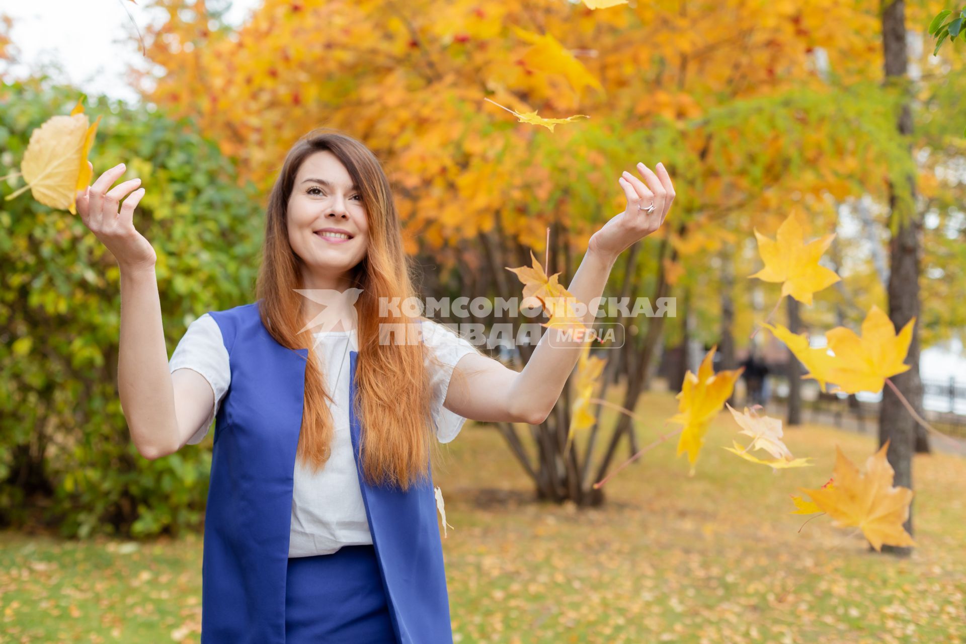 Красноярск. Девушка подкидывает листья в осеннем парке.