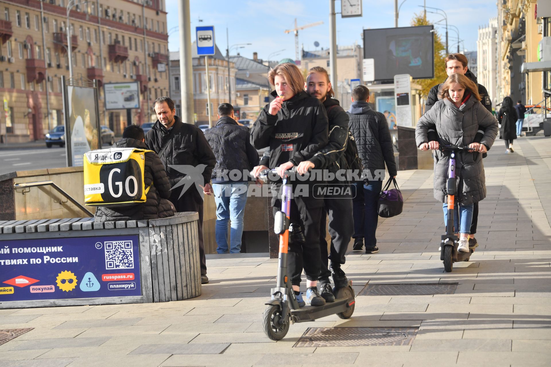 Москва.  Молодые люди едут на самокатах.