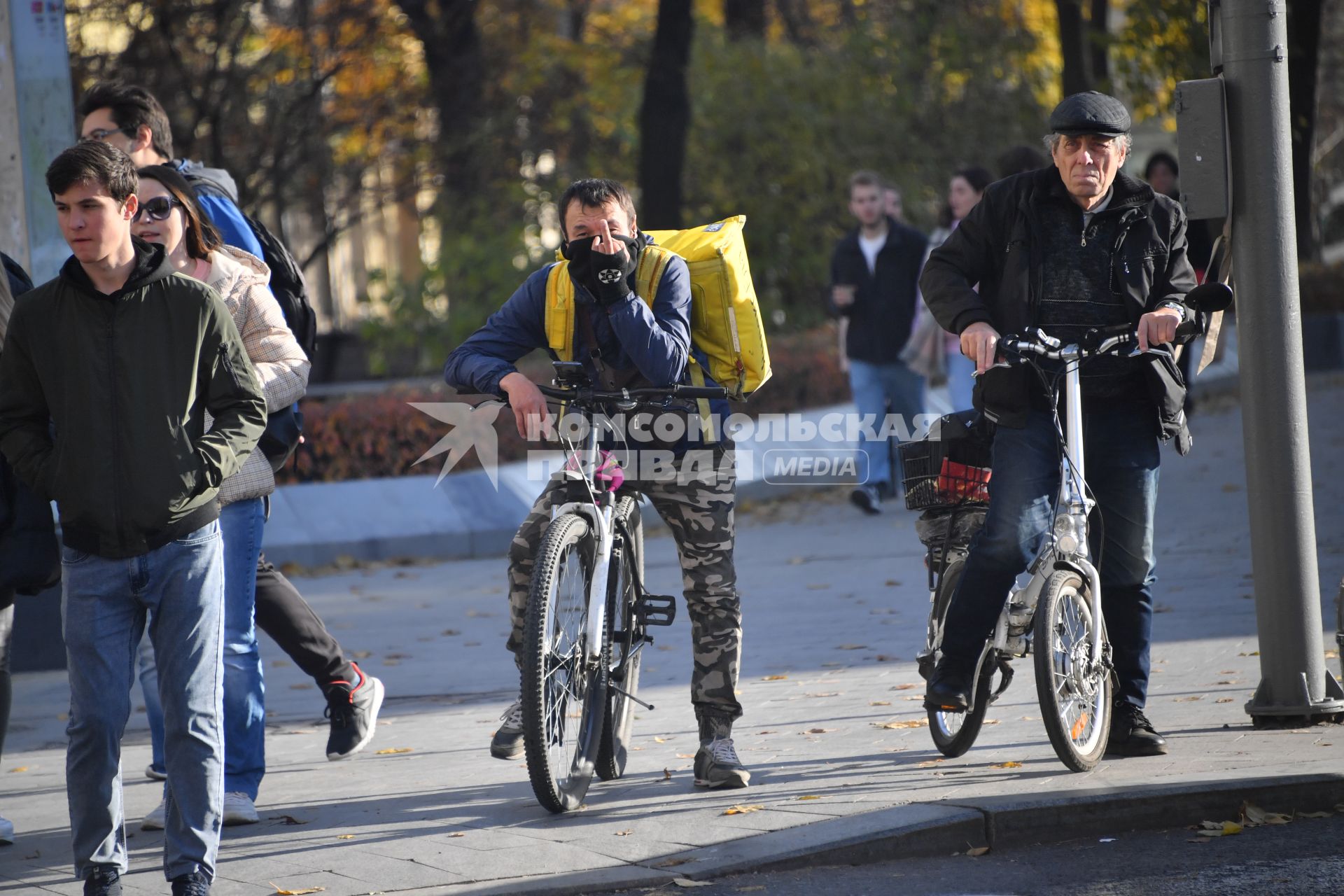 Москва.  Сотрудник службы доставки на пешеходном переходе.