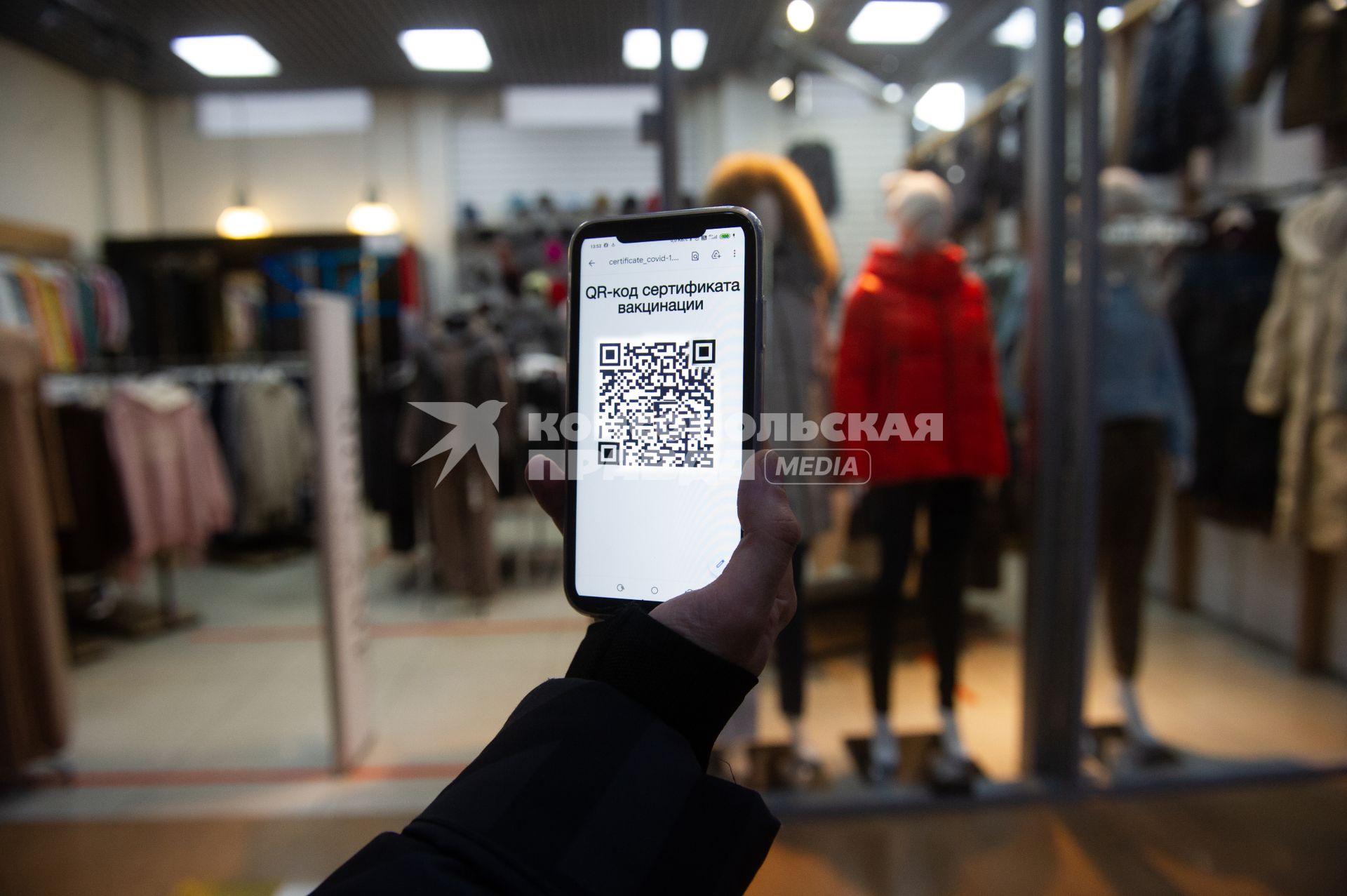 Санкт-Петербург. Юноша с мобильный телефоном, на экране которого отображен QR-код, идет по торговому центру.