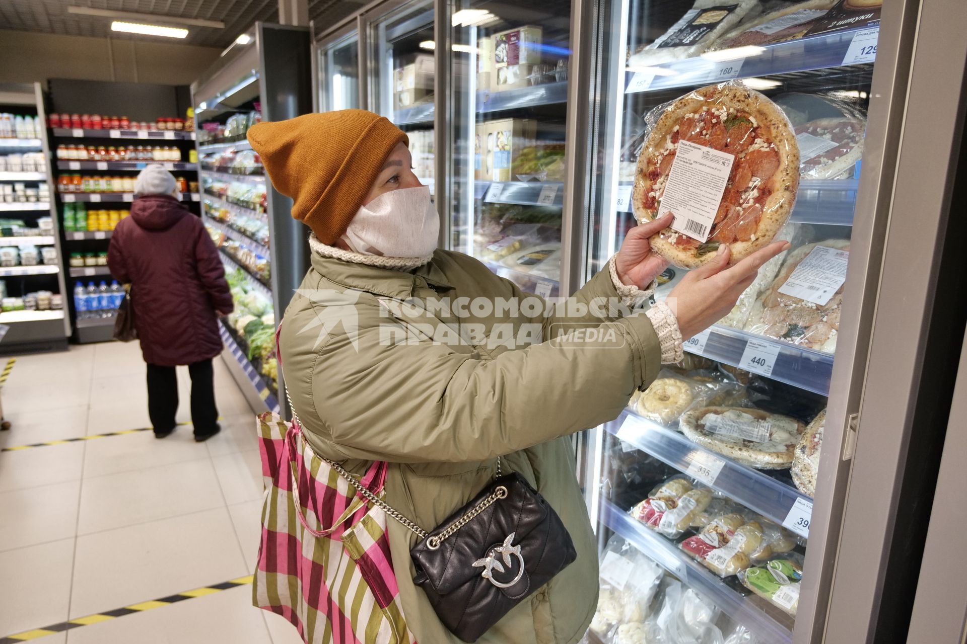 Самара. Женщина держит в руках замороженную пиццу в продуктовом магазине.