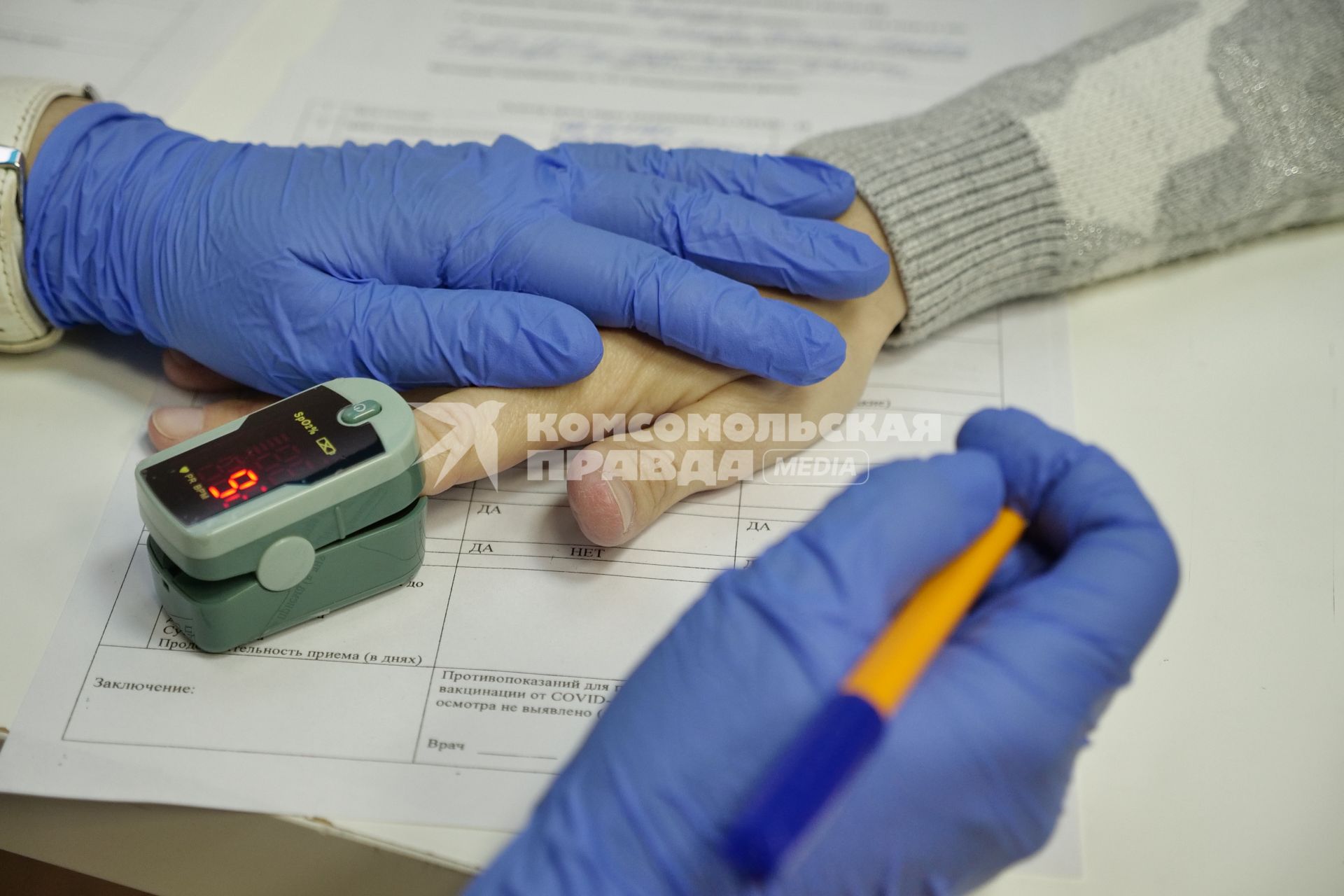Самара. Врач измеряет пульсоксиметром кислород в крови пациента перед вакцинацией от COVID-19.