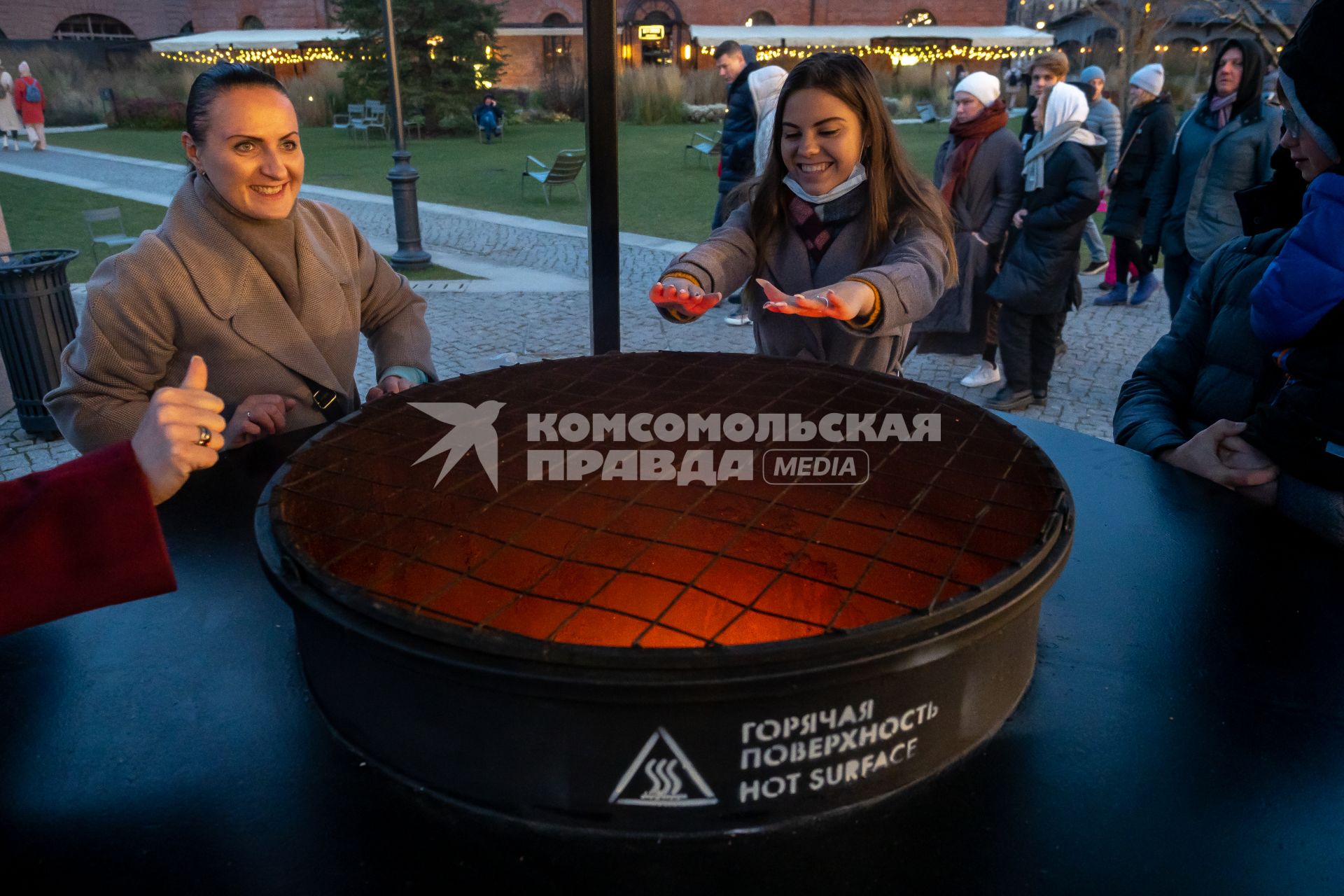 Санкт-Петрбург. Каток в `Новой Голландии`. Девушки греют руки над жаровней.