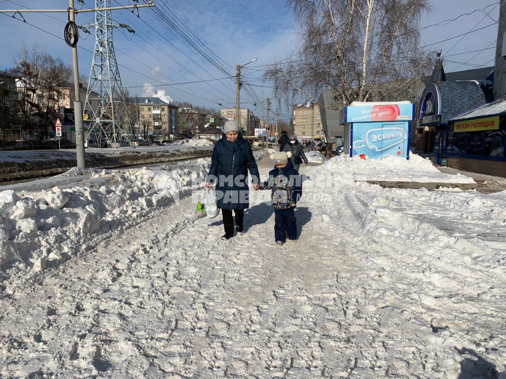 Томск. Женщина с ребенком идут по тротуару на одной из улиц города.