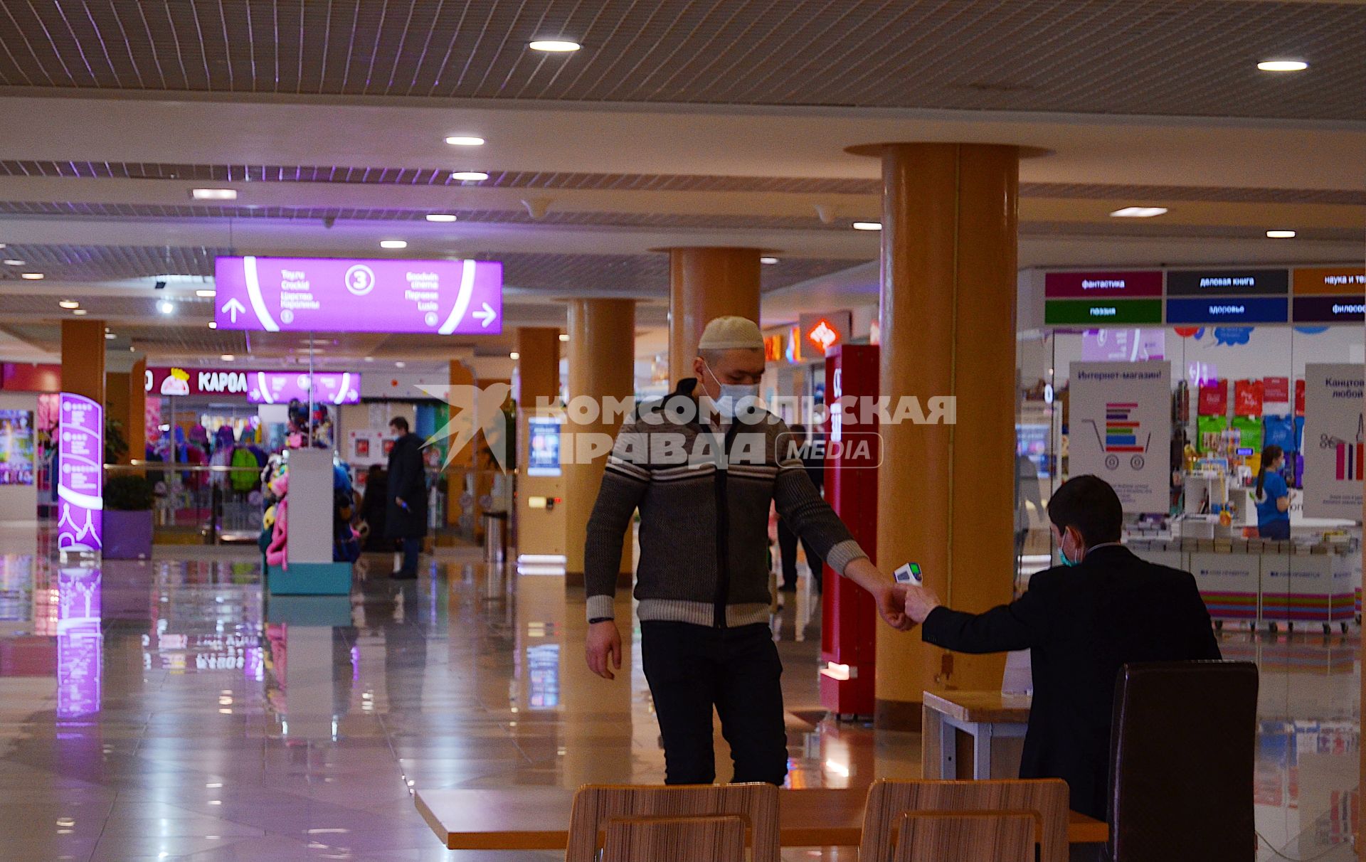 Томск. Сотрудник службы безопасности измеряет температуру тела бесконтактным способом посетителю ТРЦ `Изумрудный город`, в период пандемии коронавируса COVID-19.