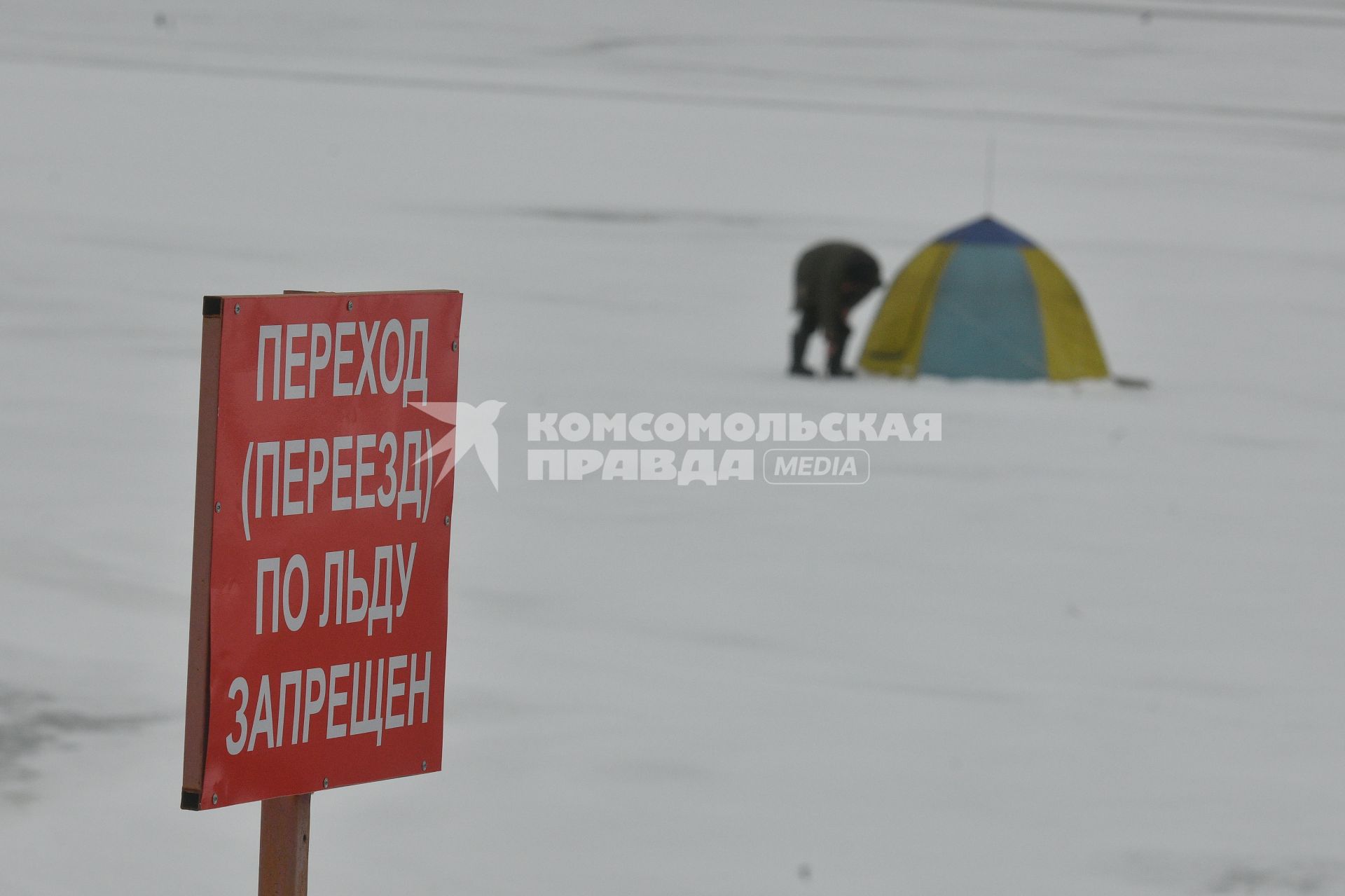 Екатеринбург. Рыбак на льду городского пруда под табличкой с надписью \'переход (переезд) по льду запрещен\'