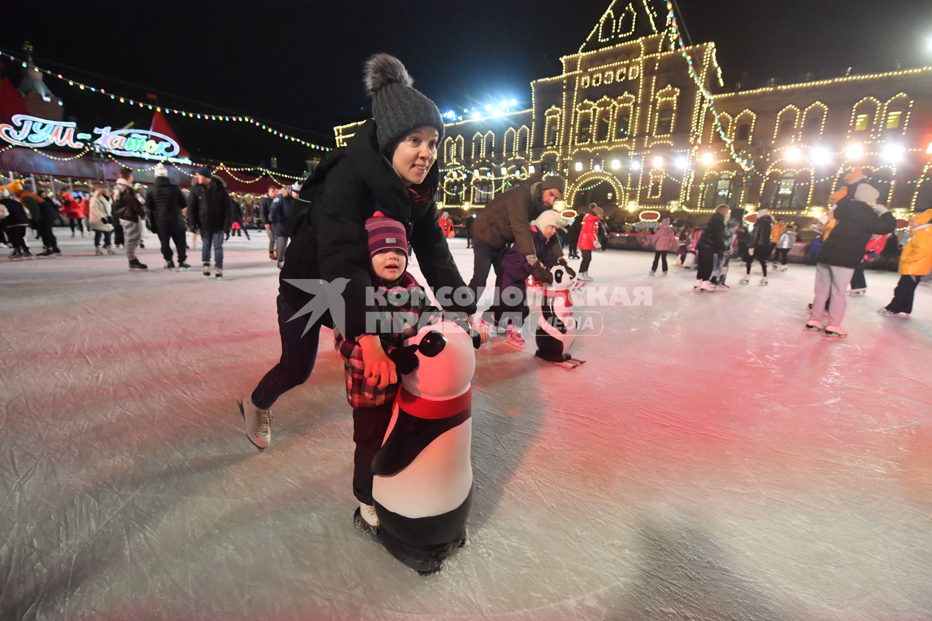 Москва. Женщина с ребенком катаются на коньках с помощью поддерживающей стойки на открытии ГУМ-катка на Красной площади.