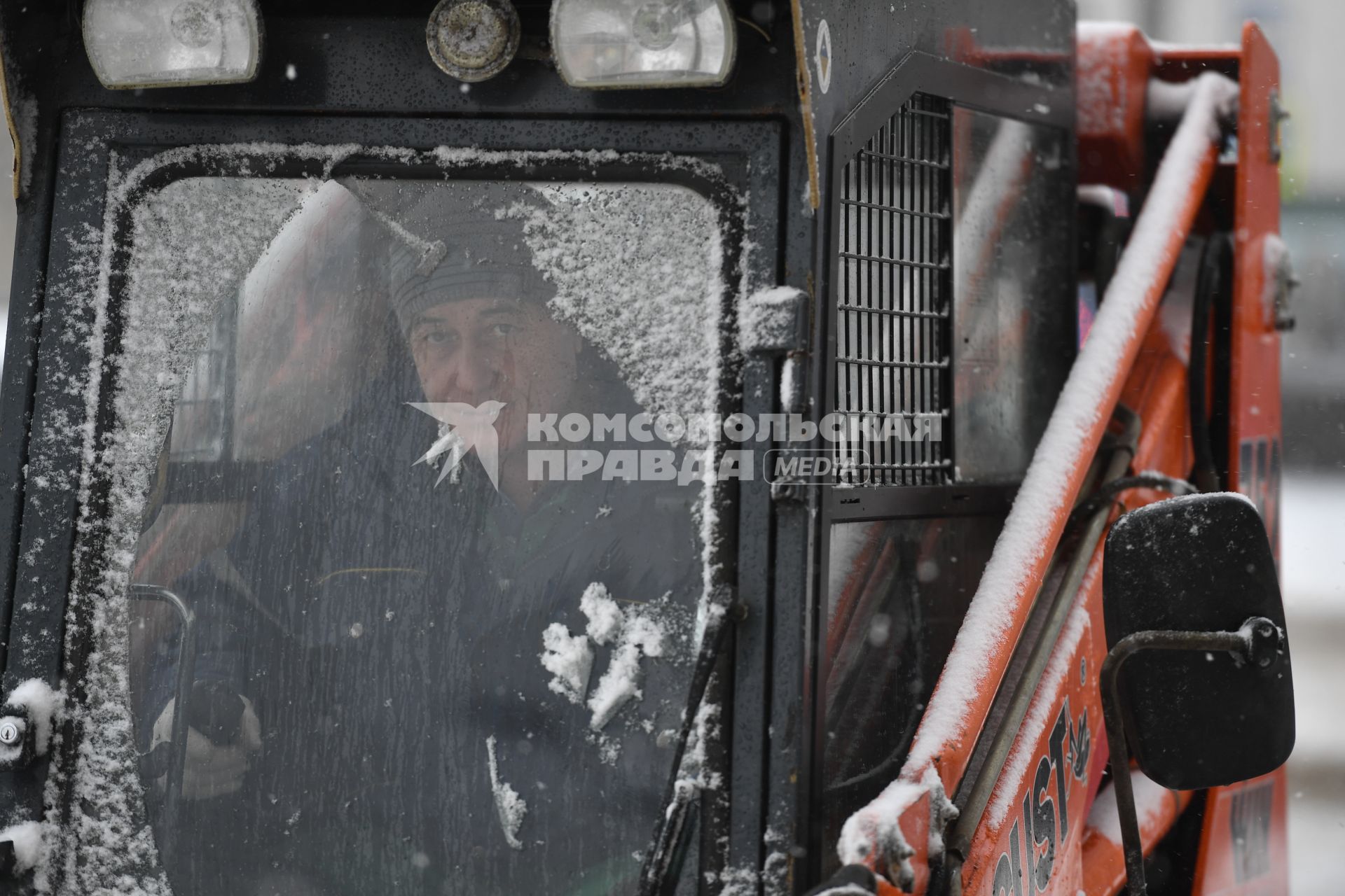 Москва. Сотрудник коммунальных служб в кабине снегоуборочной машины на улице города.