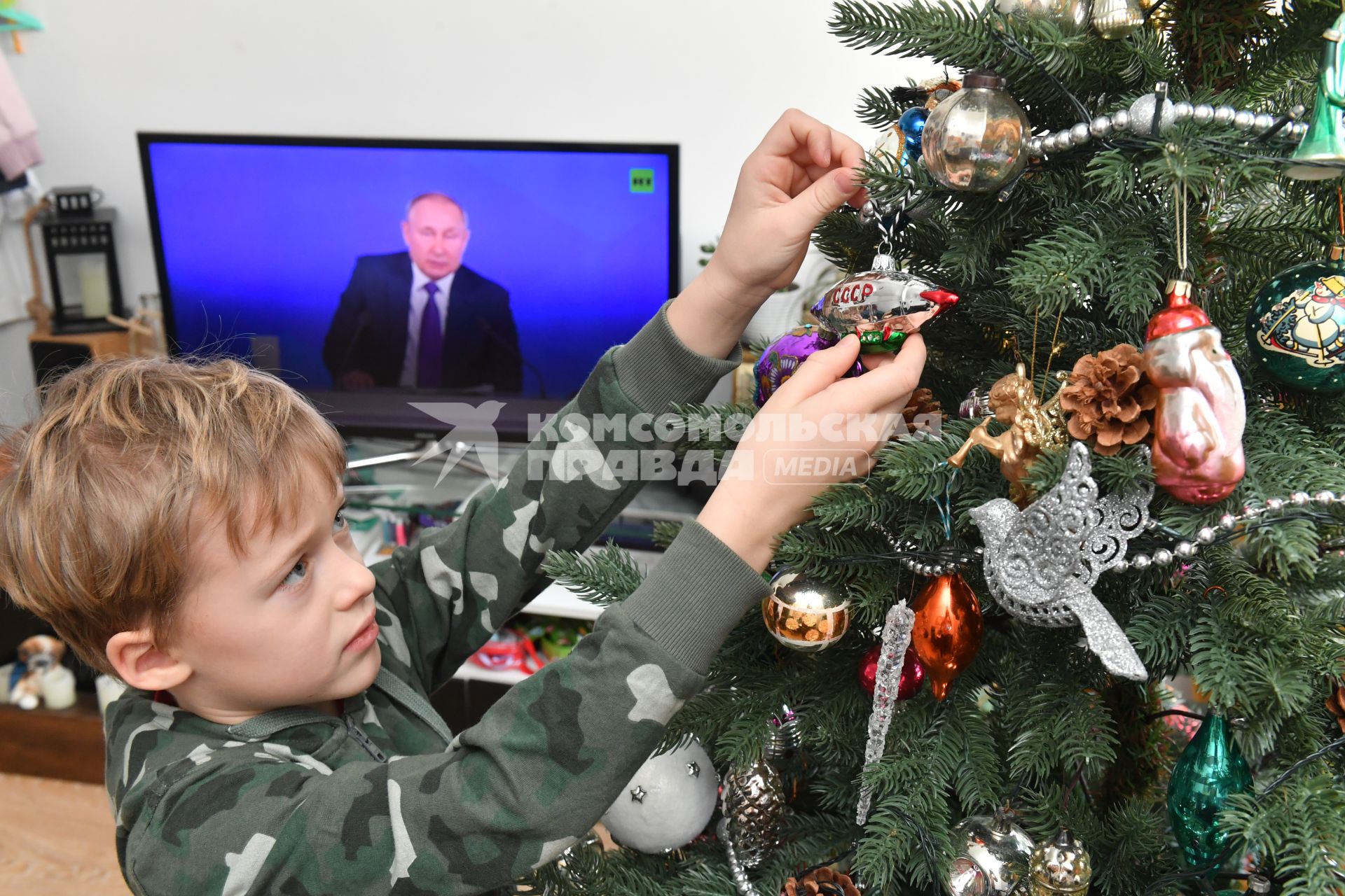 Москва. Мальчик наряжает новогоднюю елку во время просмотра трансляции ежегодной пресс-конференции президента РФ Владимира Путина.