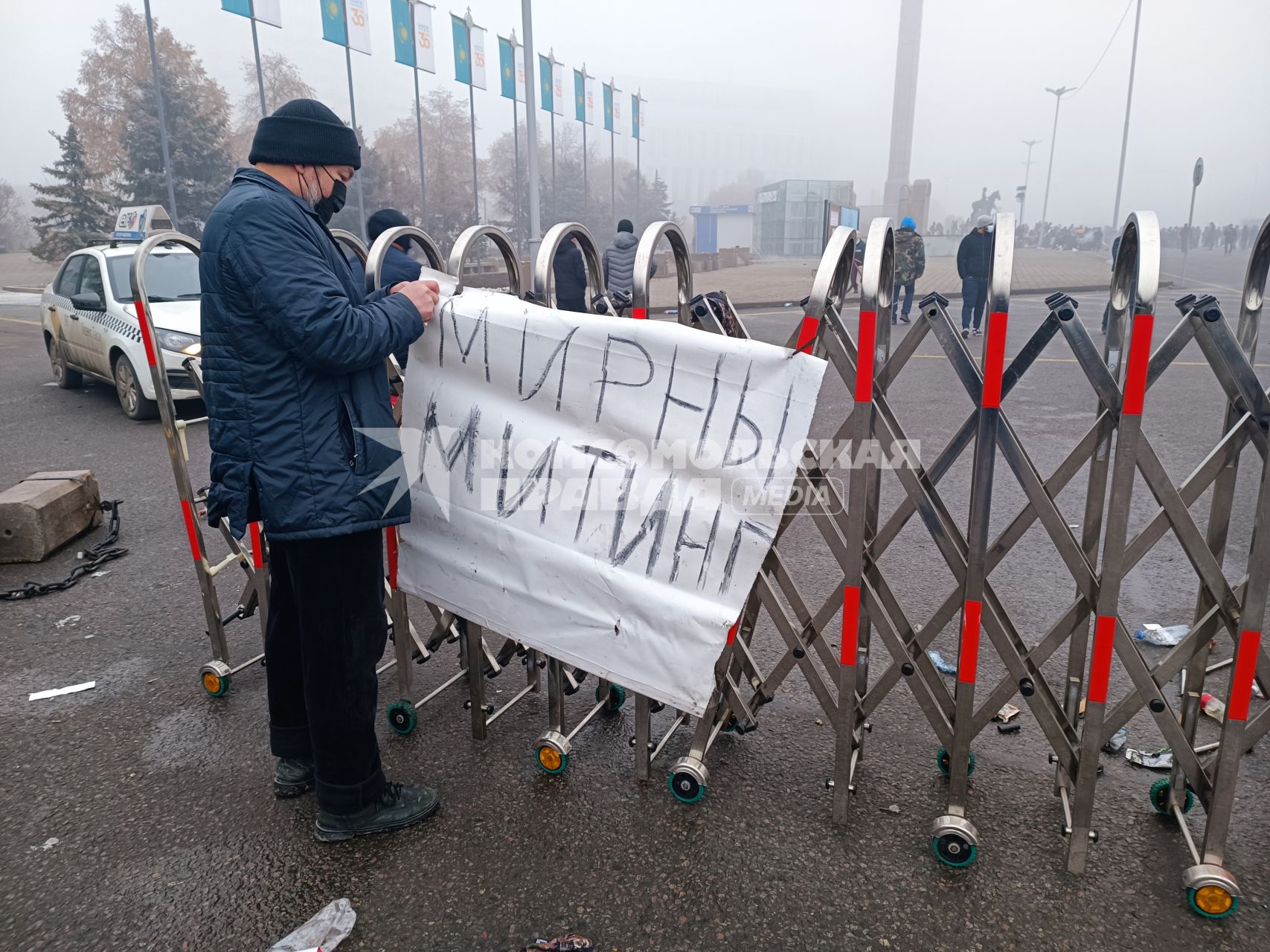 Казахстан. г.Алма-Ата. Мужчина вешает на ограждение плакат `Мирный митинг`. В Казахстане прошли массовые акции протестов, вызванные ростом цен на сжиженный нефтяной газ, которые потом переросли в беспорядки и погромы.