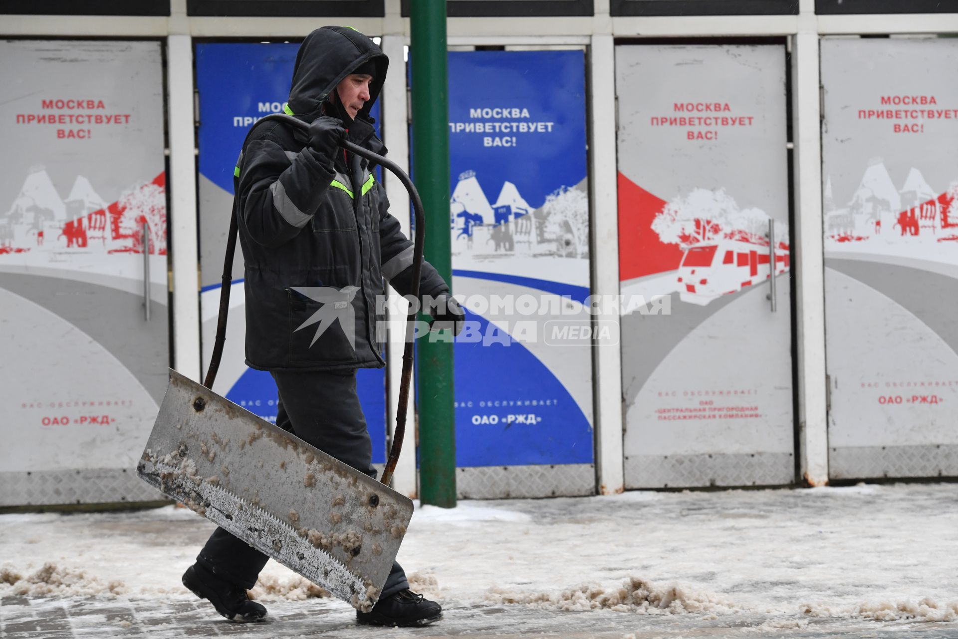 Москва. Дворник убирает снег на Ярославском вокзале. Надпись на двери `Москва приветствует вас!`.