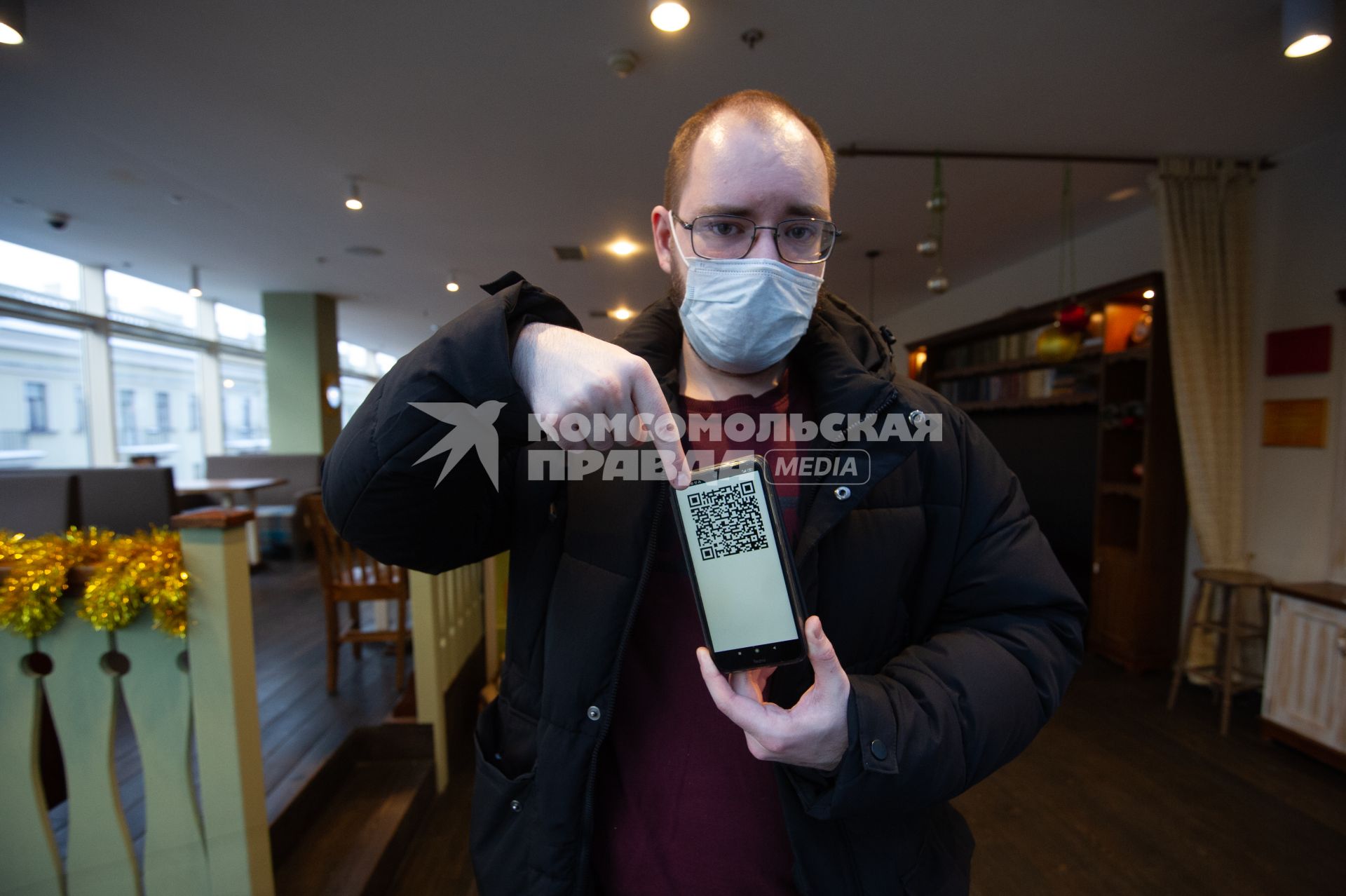 Санкт-Петербург. Мужчина демонстирует QR-код на экране мобильного телефона при входе в ресторан.