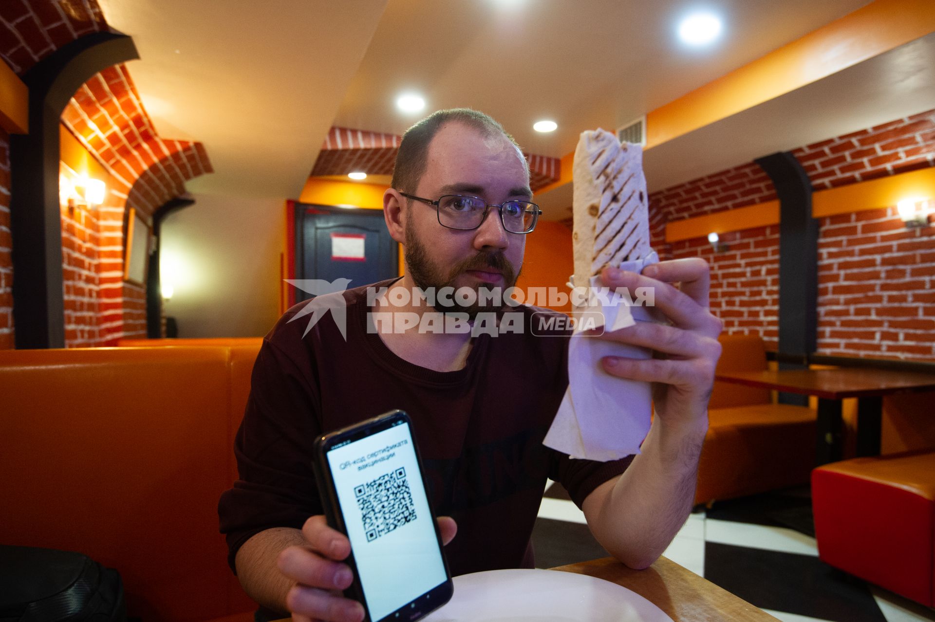 Санкт-Петербург. Мужчина демонстирует QR-код на экране мобильного телефона в кафе.