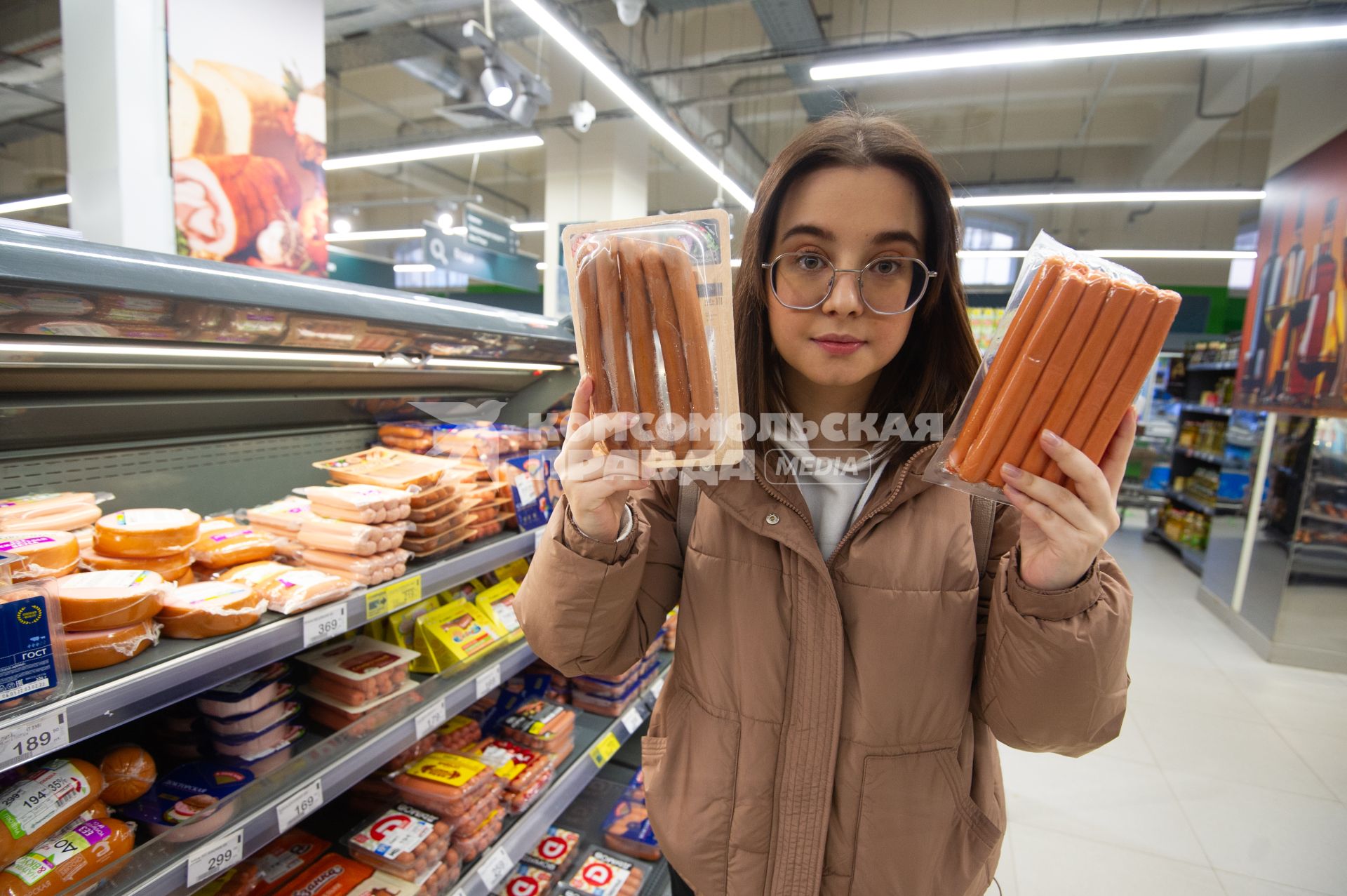 Санкт-Петербург. Девушка выбирает сосиски в продуктовом магазине.