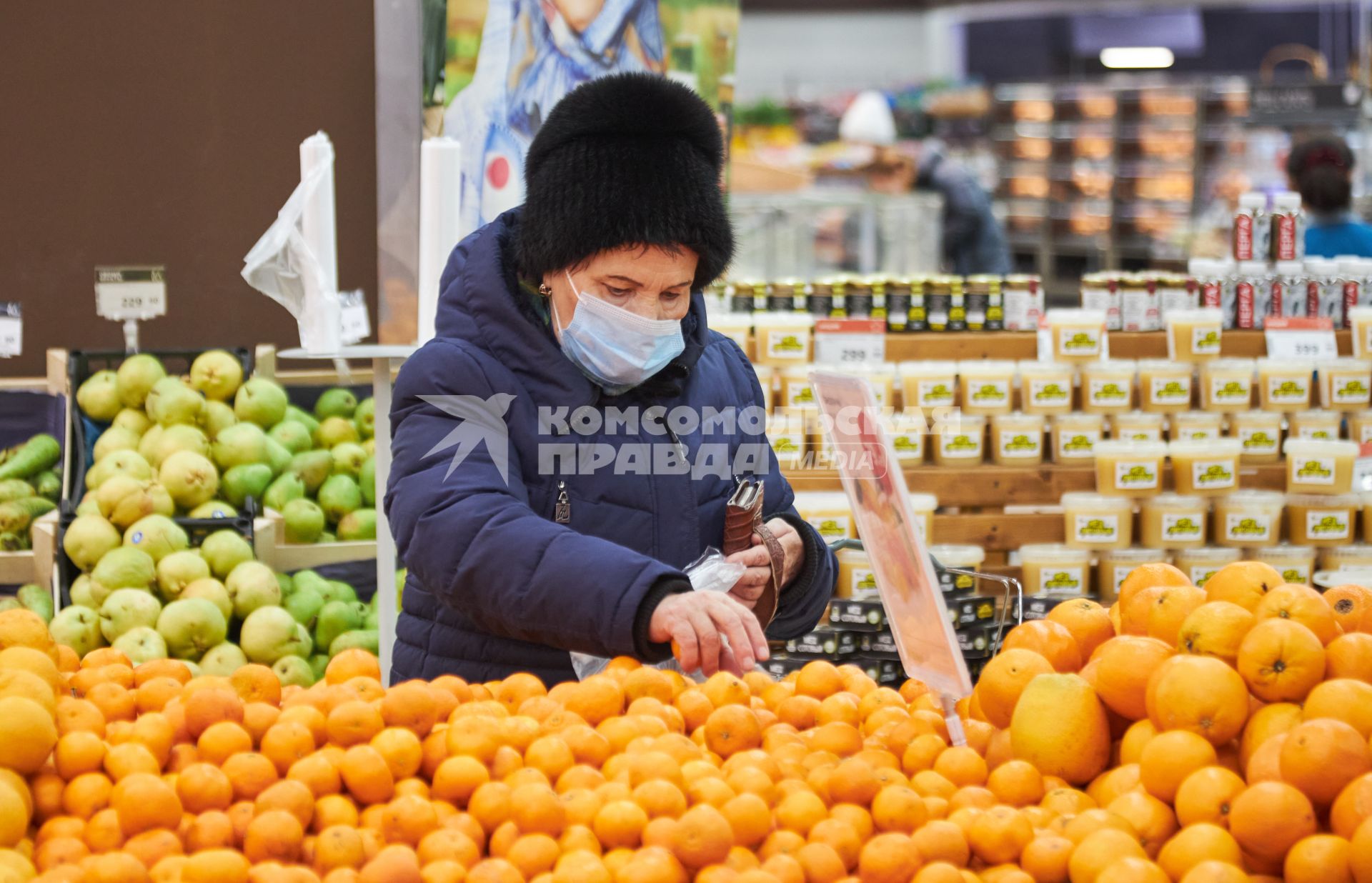 Пермь. Женщина выбирает мандарины в магазине.