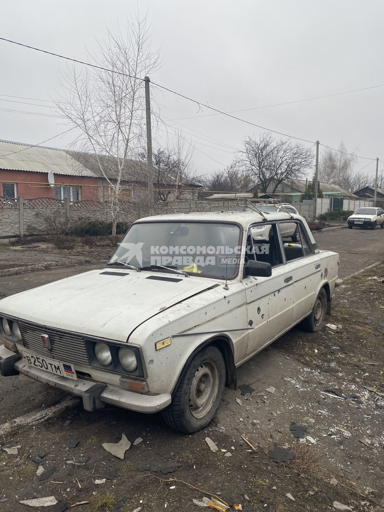 Донецкая область. Последствия обстрела поселка украинской артиллерией. У входа в один из домов посеченный осколками автомобиль `Жигули`.