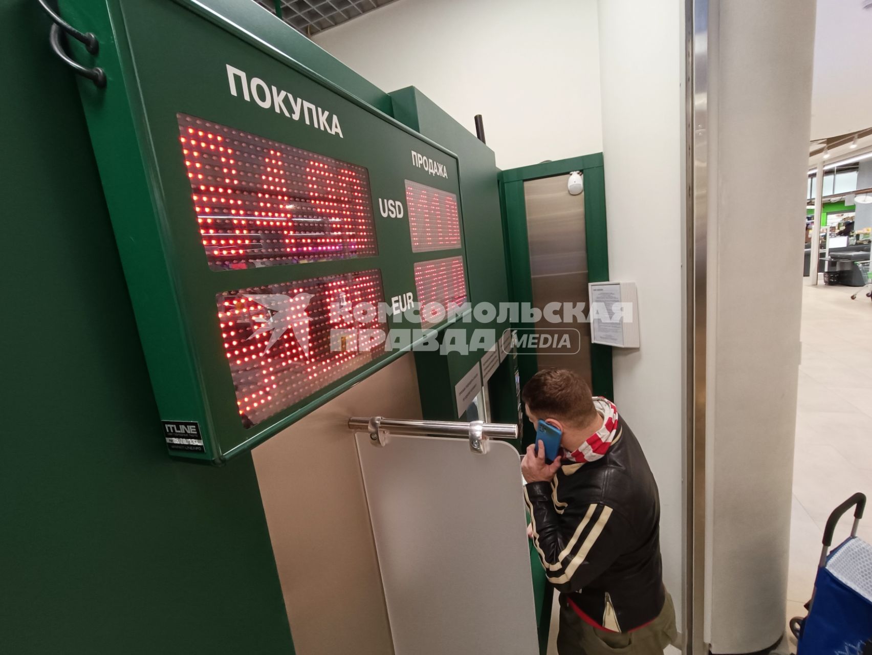 Москва.  Мужчина у банкомата в торговом центре.