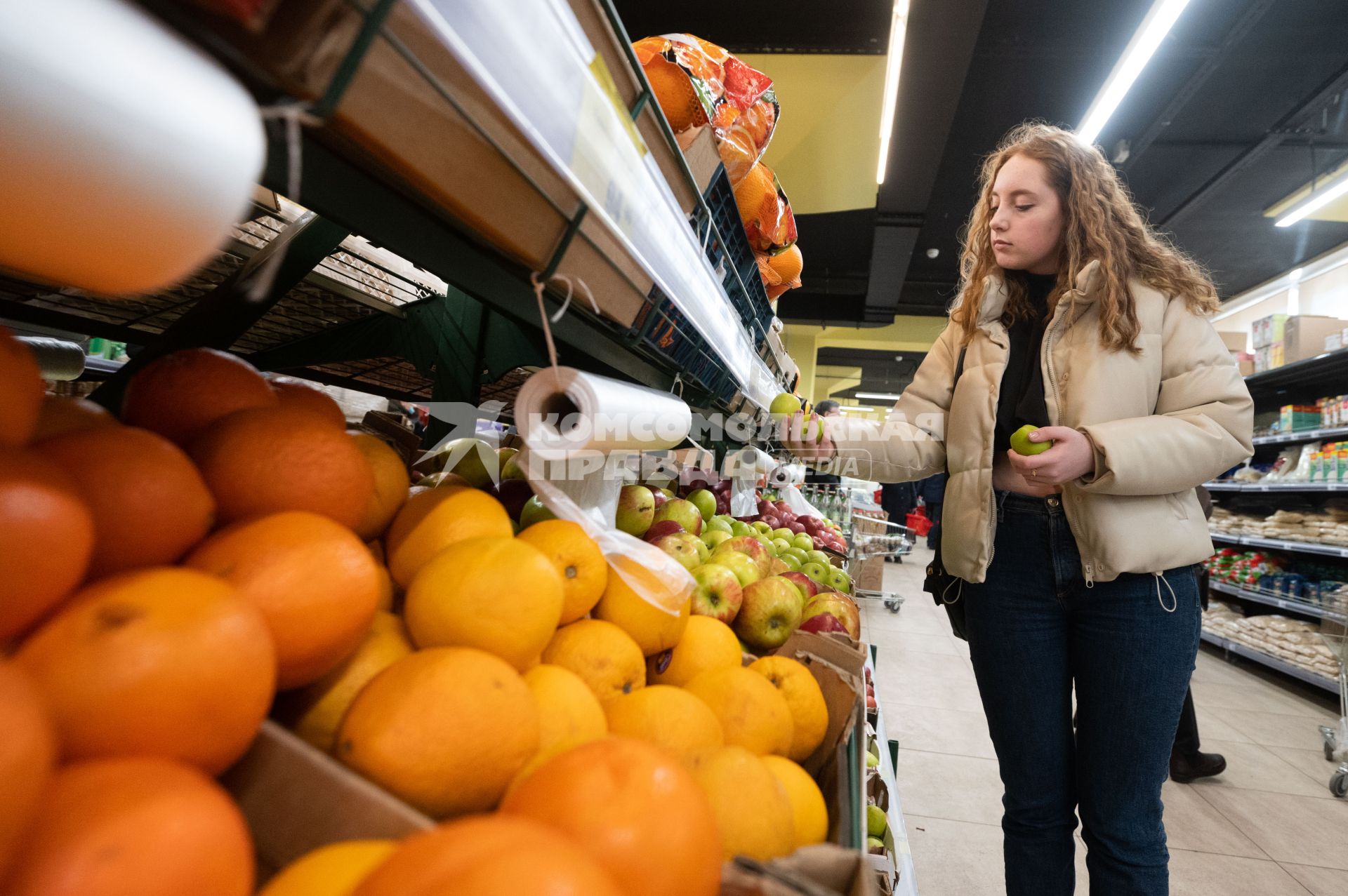 Санкт-Петербург. Девушка выбирает яблоки в продуктовом магазине.