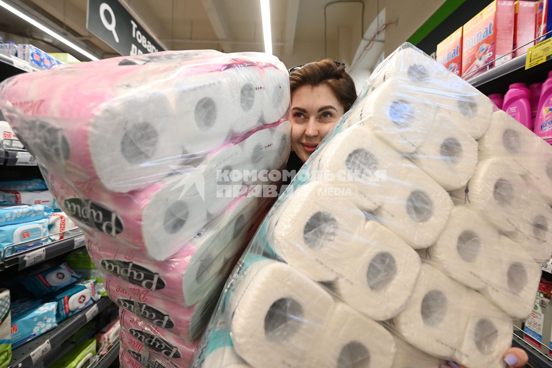 Санкт-Петербург. Девушка держит в руках упаковки с туалетной бумагой в магазине.