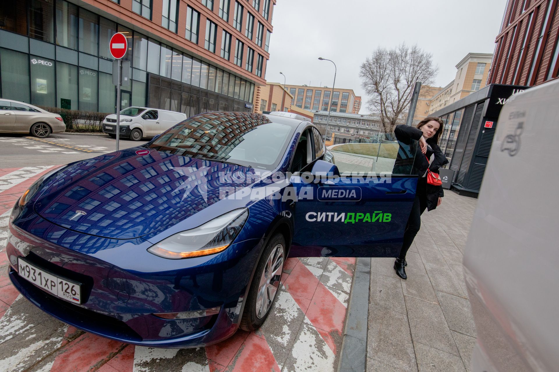 Москва. Девушка у электрокара Tesla Model Y оператора каршеринга `Ситидрайв`.