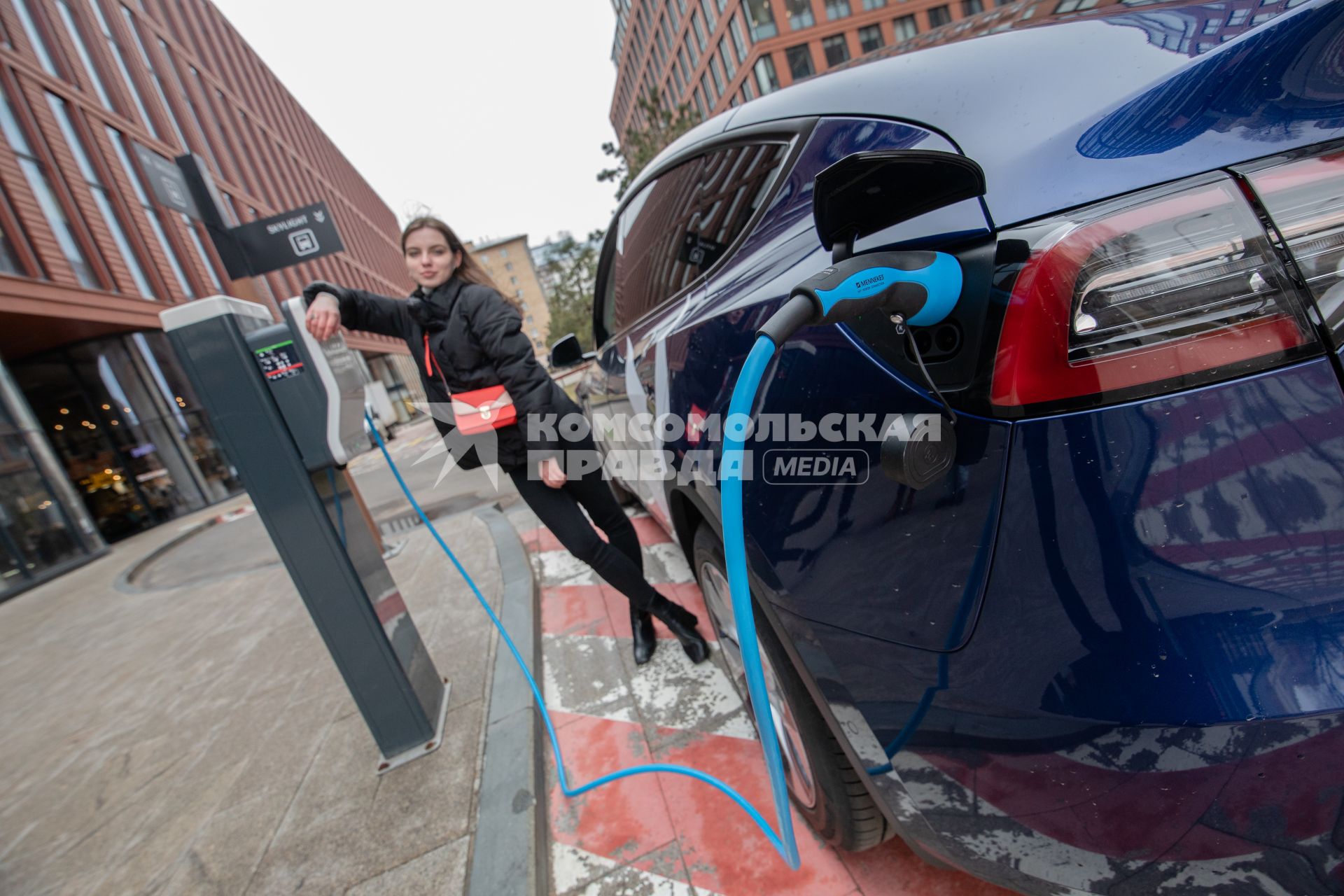 Москва. Девушка во время зарядки электрокара Tesla Model Y оператора каршеринга `Ситидрайв`.