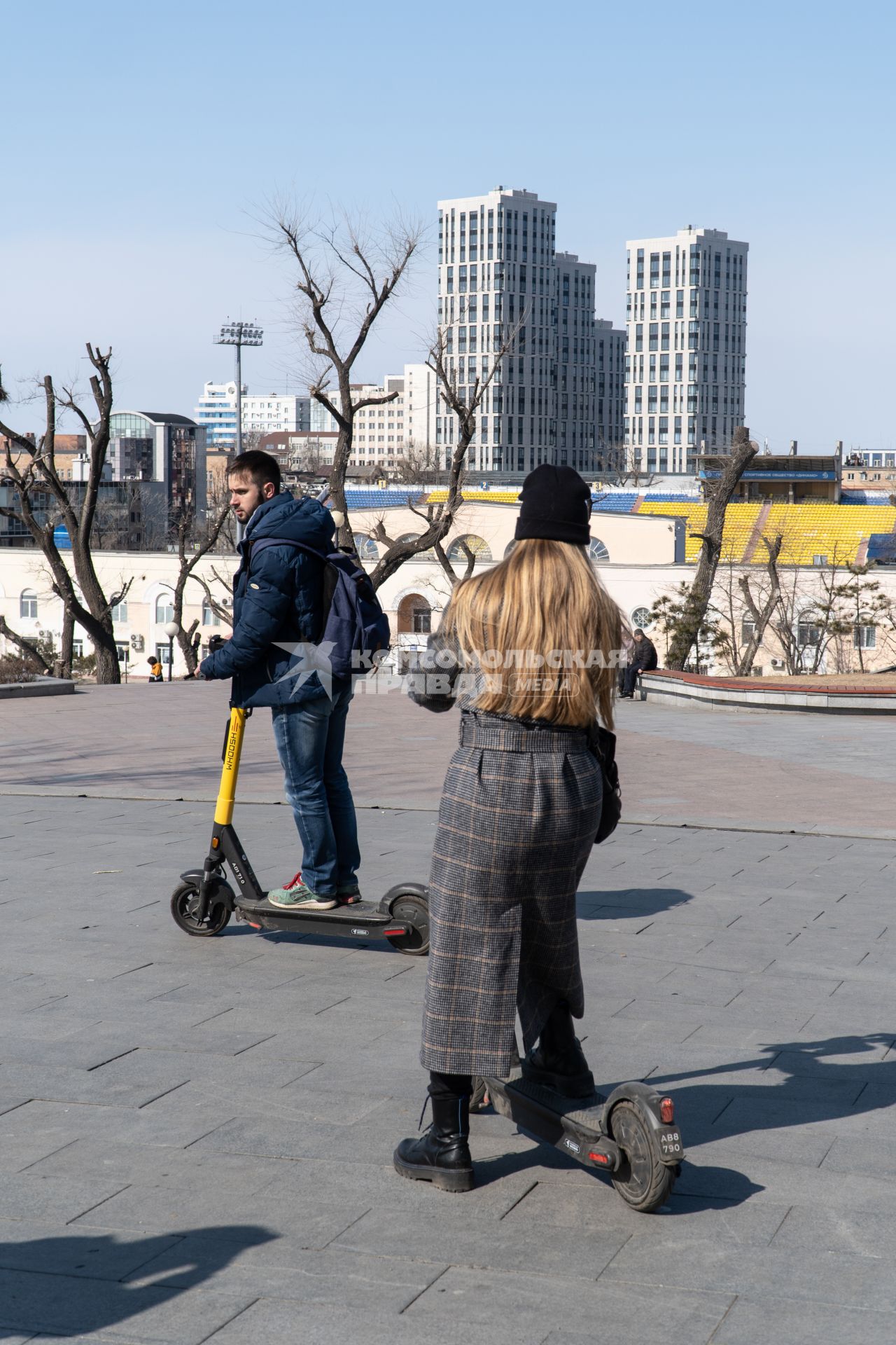 Владивосток. Молодые люди катаются на электросамокате.