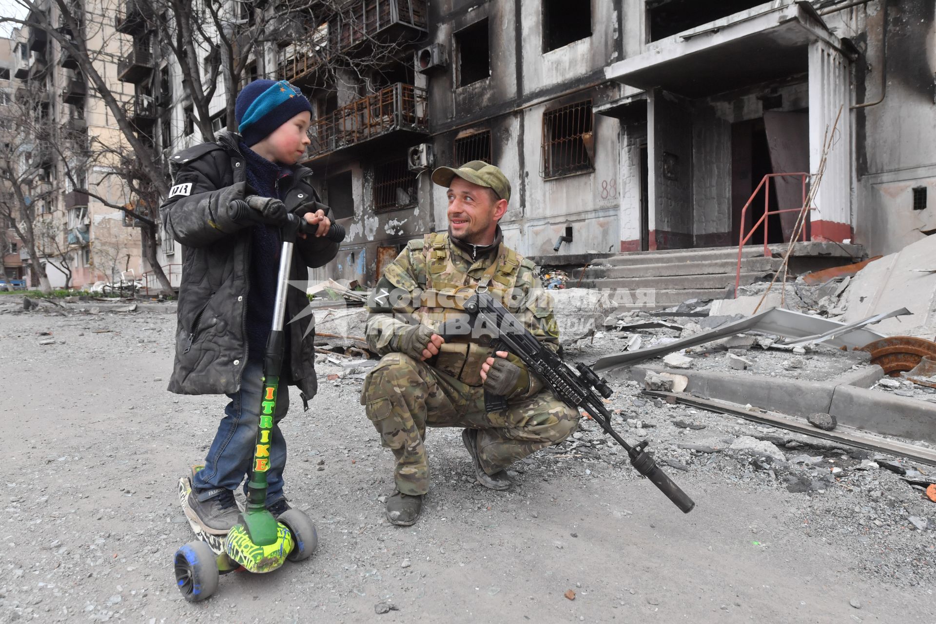 Украина. г.Мариуполь. Мальчик и военнослужащий рядом с жилым домом, разрушенным в результате обстрелов.