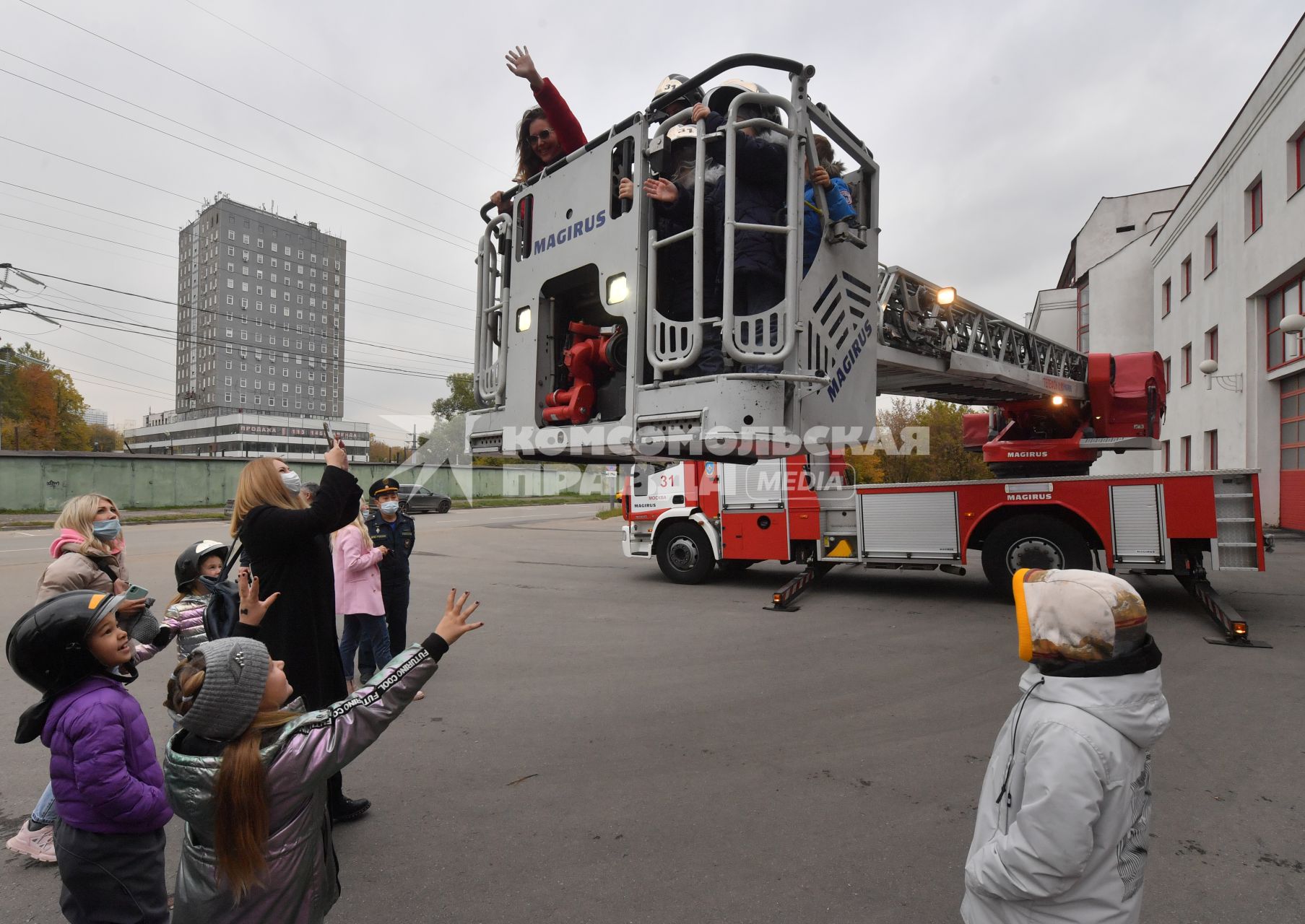 Москва. Дети в люльке пожарной машины во время посещения Московской пожарной части №31 юными спасателями и их родителями в преддверии Дня гражданской обороны и МЧС России.