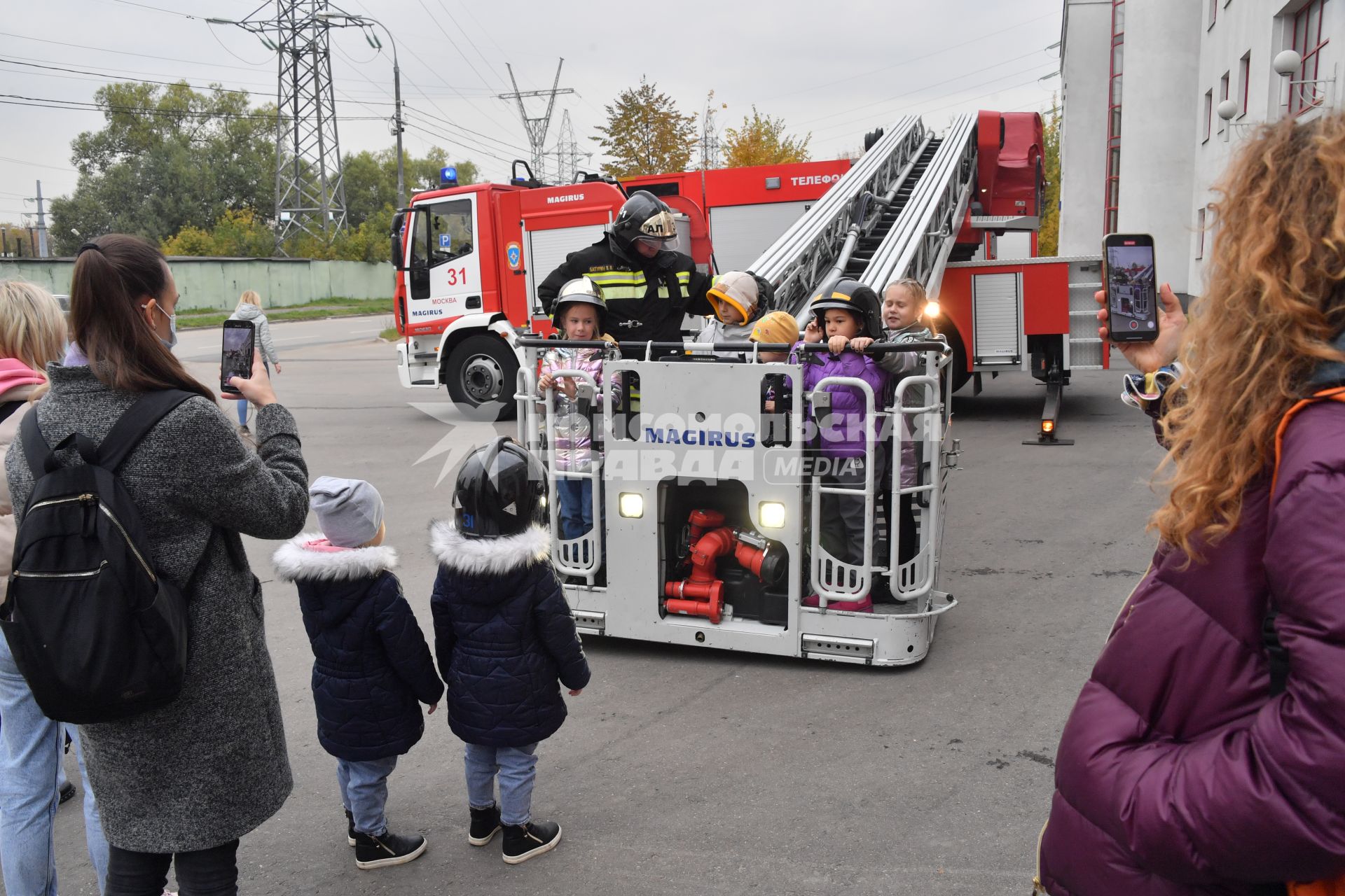 Москва. Дети в люльке пожарной машины  во время  посещения Московской пожарной части №31 юными спасателями и их родителями в преддверии Дня гражданской обороны и МЧС России.