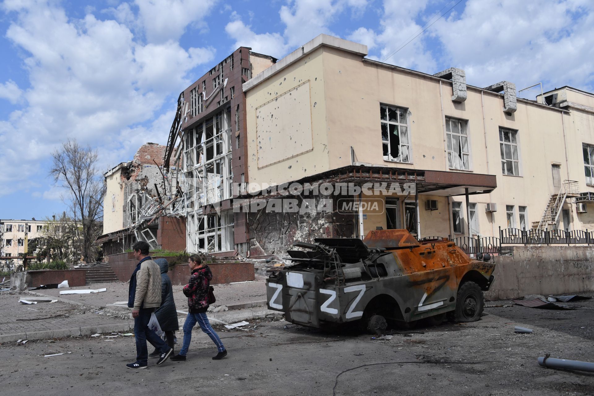 Мариуполь, Донецкая народная республика. Жители идут мимо разбитой военной техники на улице города.