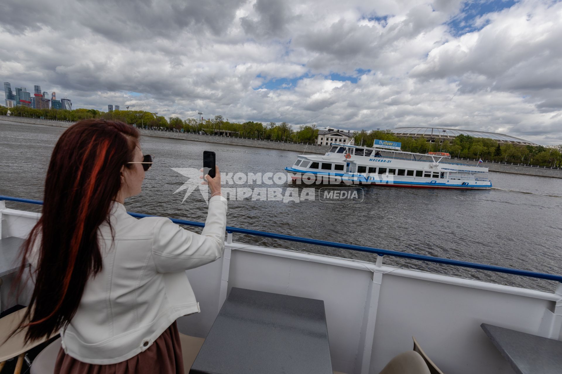 Москва. Девушка фотографирует прогулочный теплоход на Москва-реке.