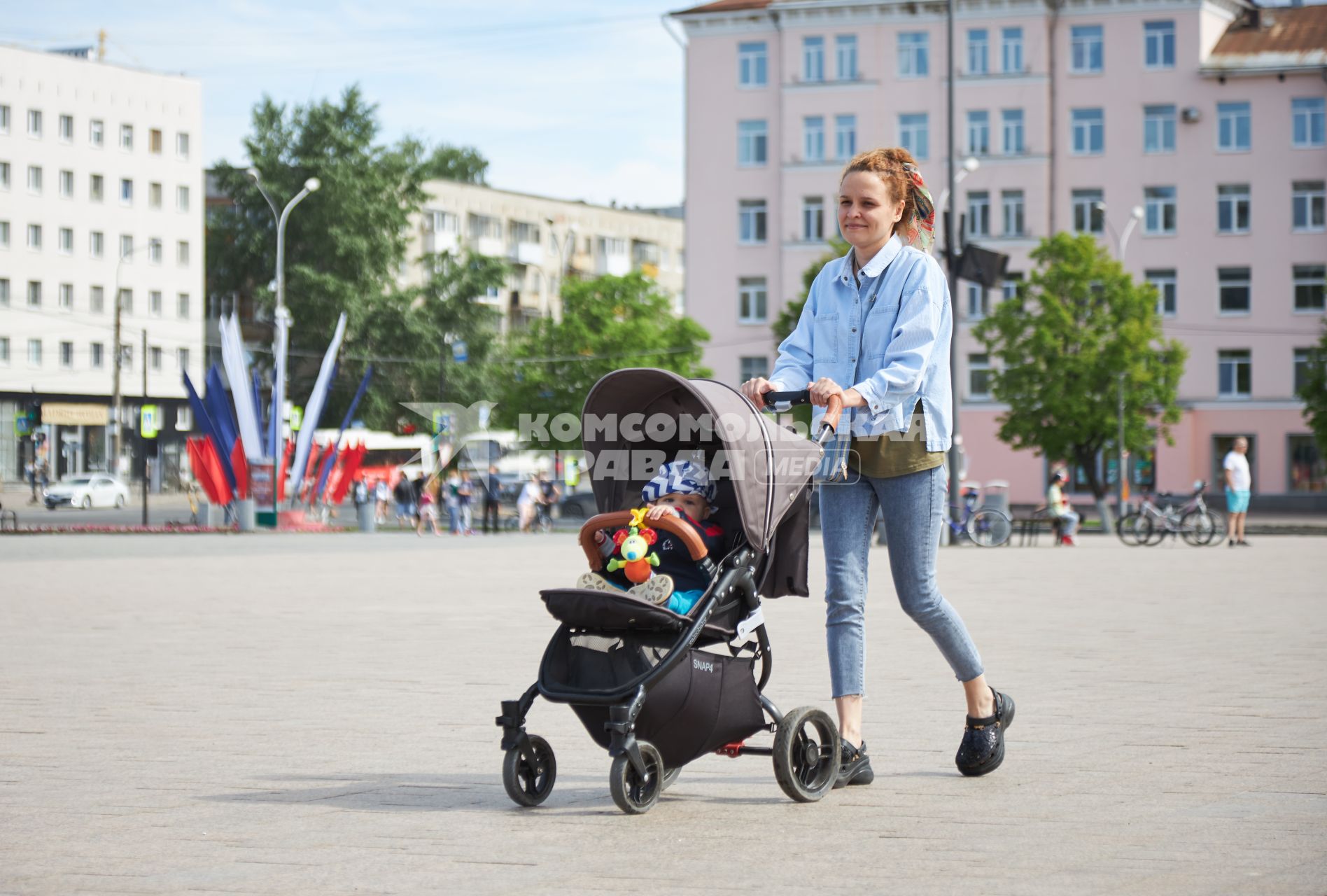 Пермь. Женщина с ребенком в детской коляске гуляют по улице.