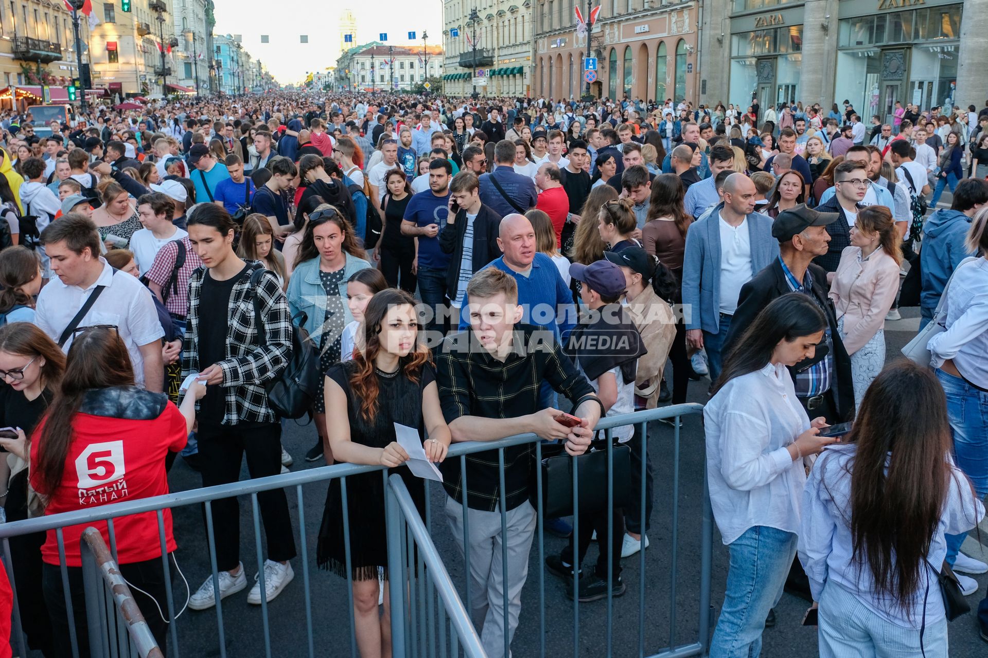 Санкт-Петербург.  Молодые люди проходят через ограждения во время  праздника выпускников `Алые паруса`.