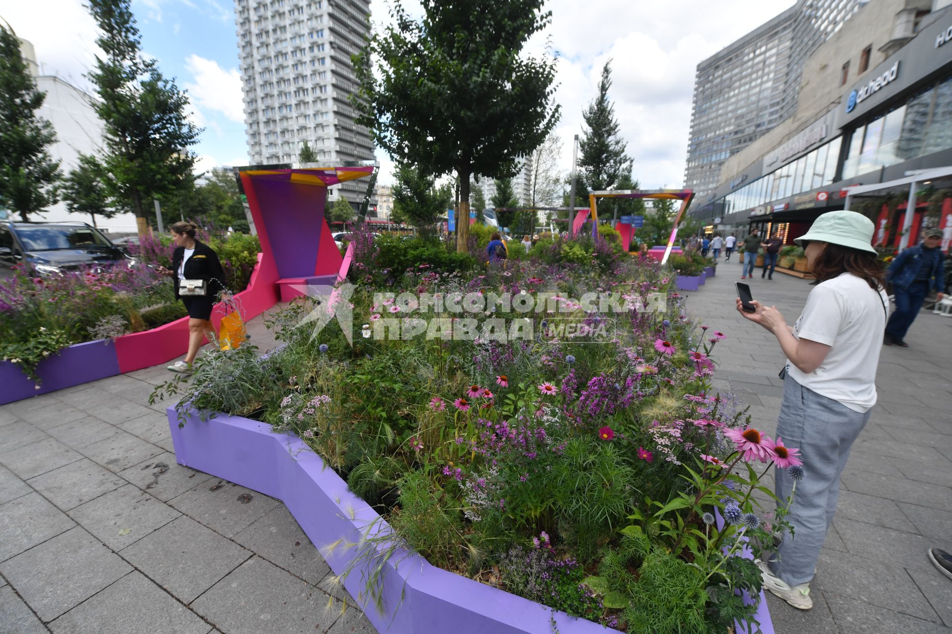 Москва. Женщина   фотографирует цветы во время фестиваля \"Цветочный джем: тропическое лето\" на Новом Арбате.