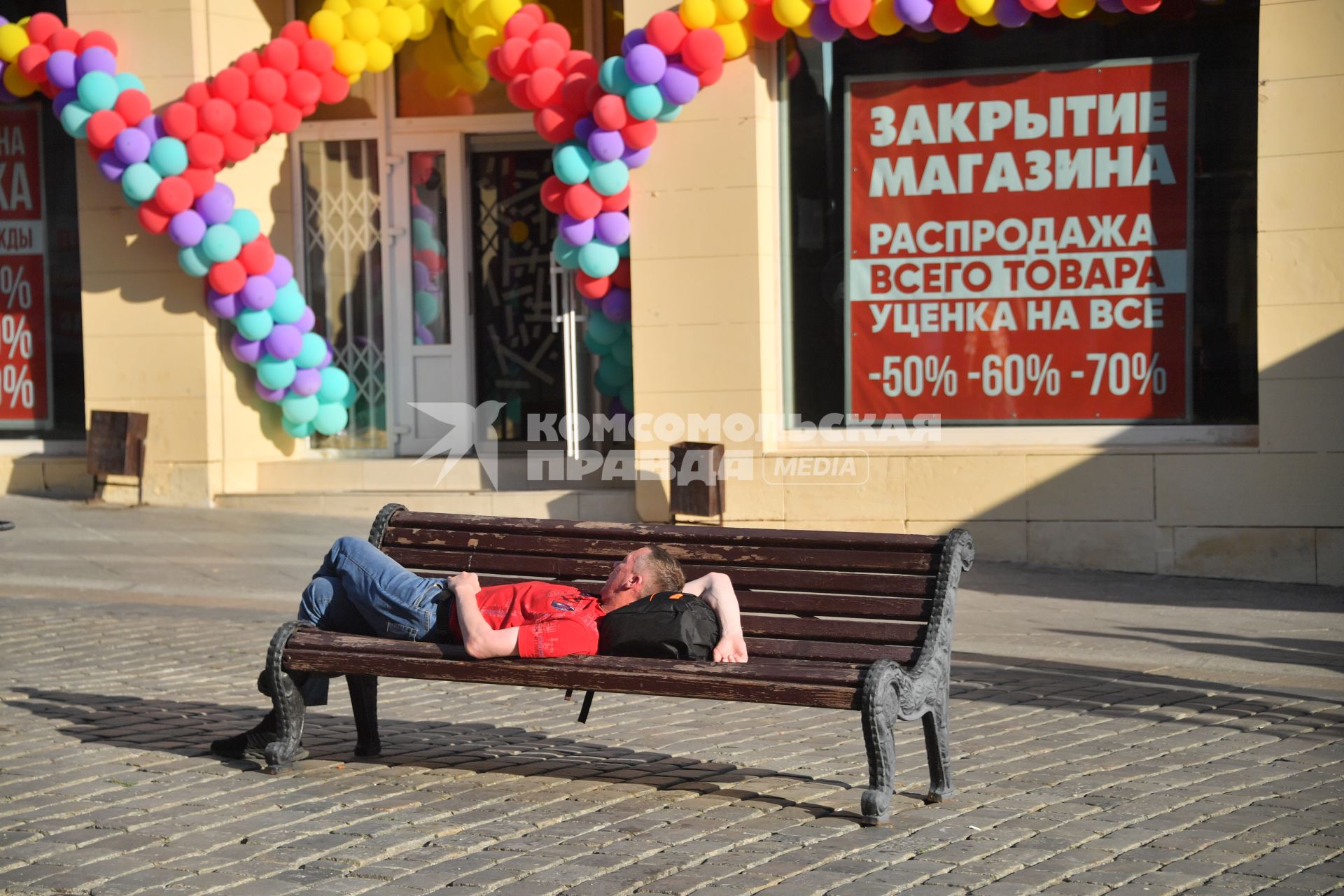 Москва.   Мужчина лежит на скамейке у магазина.