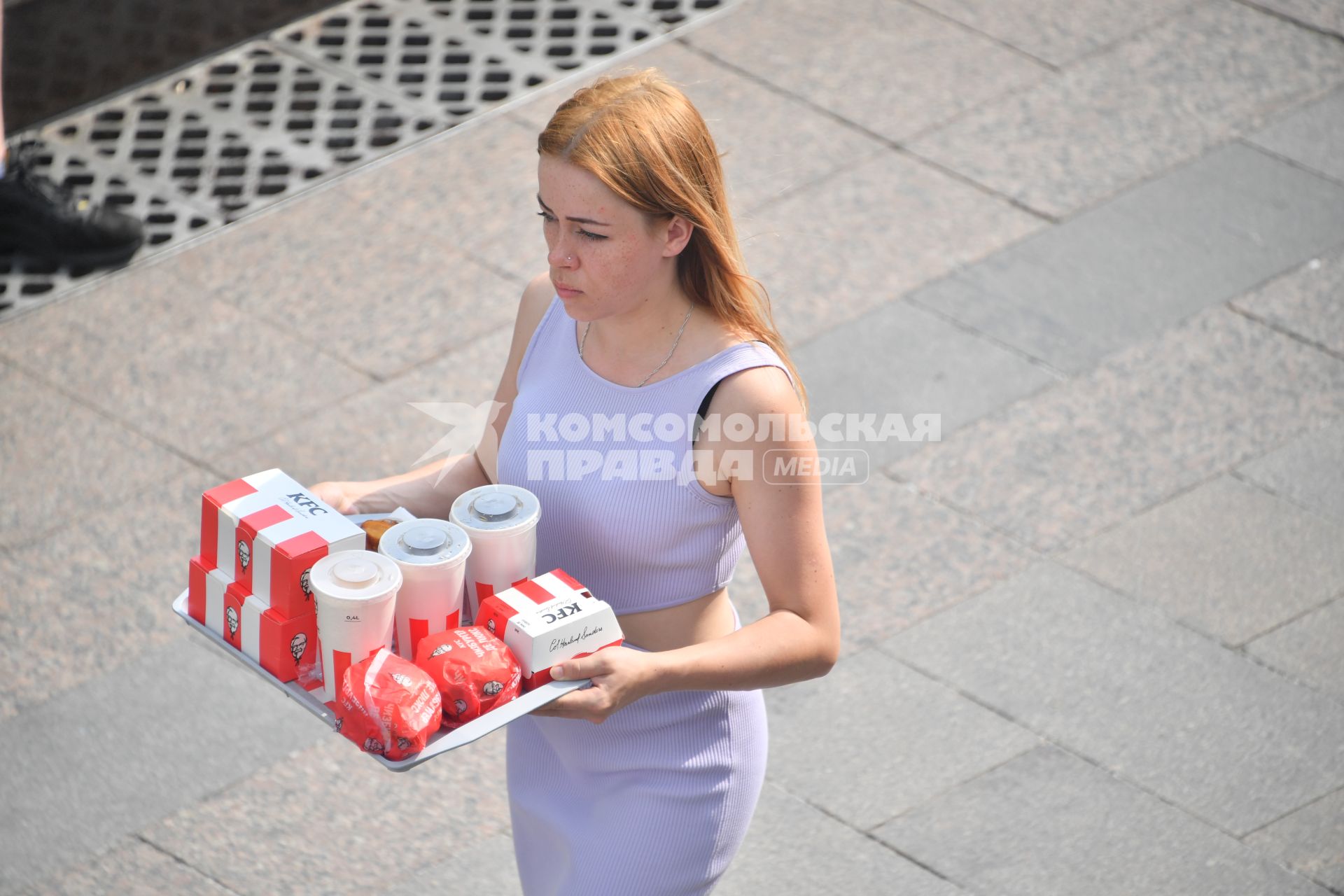 Москва.  Девушка несет еду из кафе быстрого питания KFC.