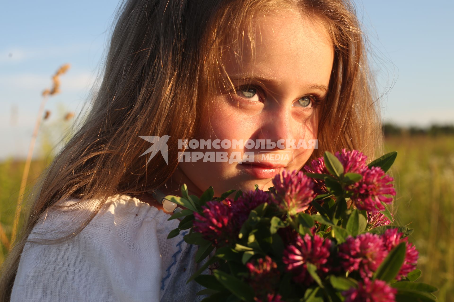 Калуга.  Девочка в русском народном костюме собирает букет полевых цветов перед началом празднования  Купалы (летнее солнцестояние) в Славянском центре `Красотынка`.