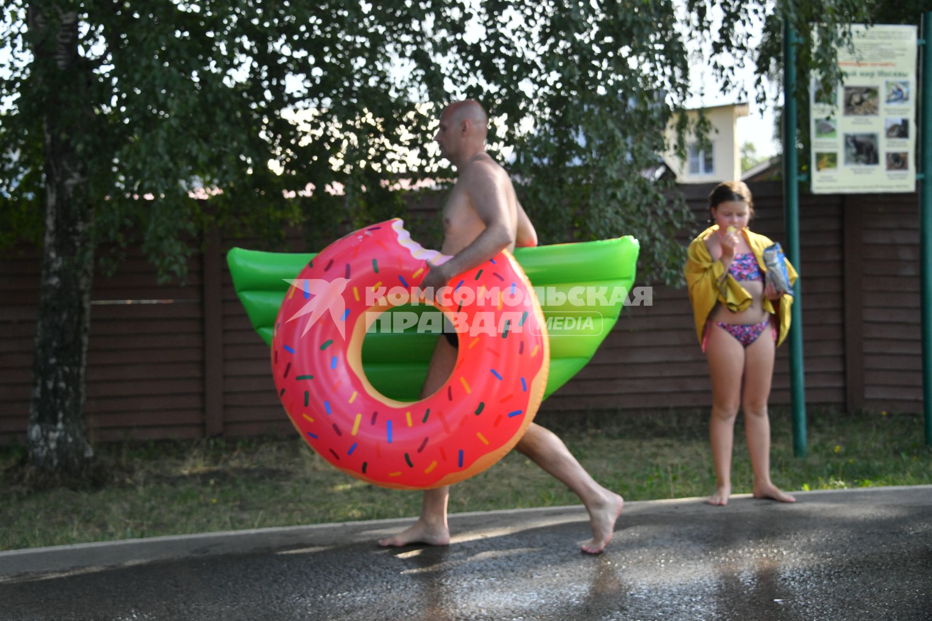 Москва. Мужчина с надувным кругом в виде пончика идет на пляже Косинского озера.