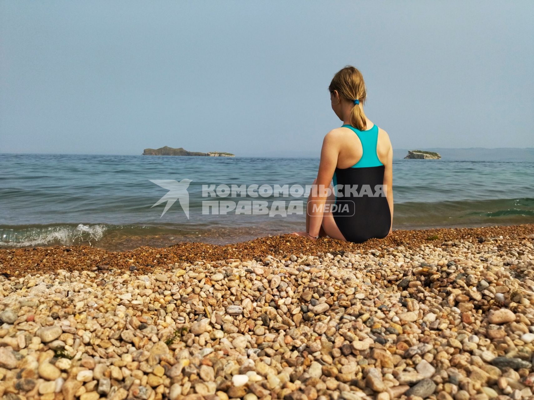 Иркутская область. Девушка сидит на берегу озера Байкал.