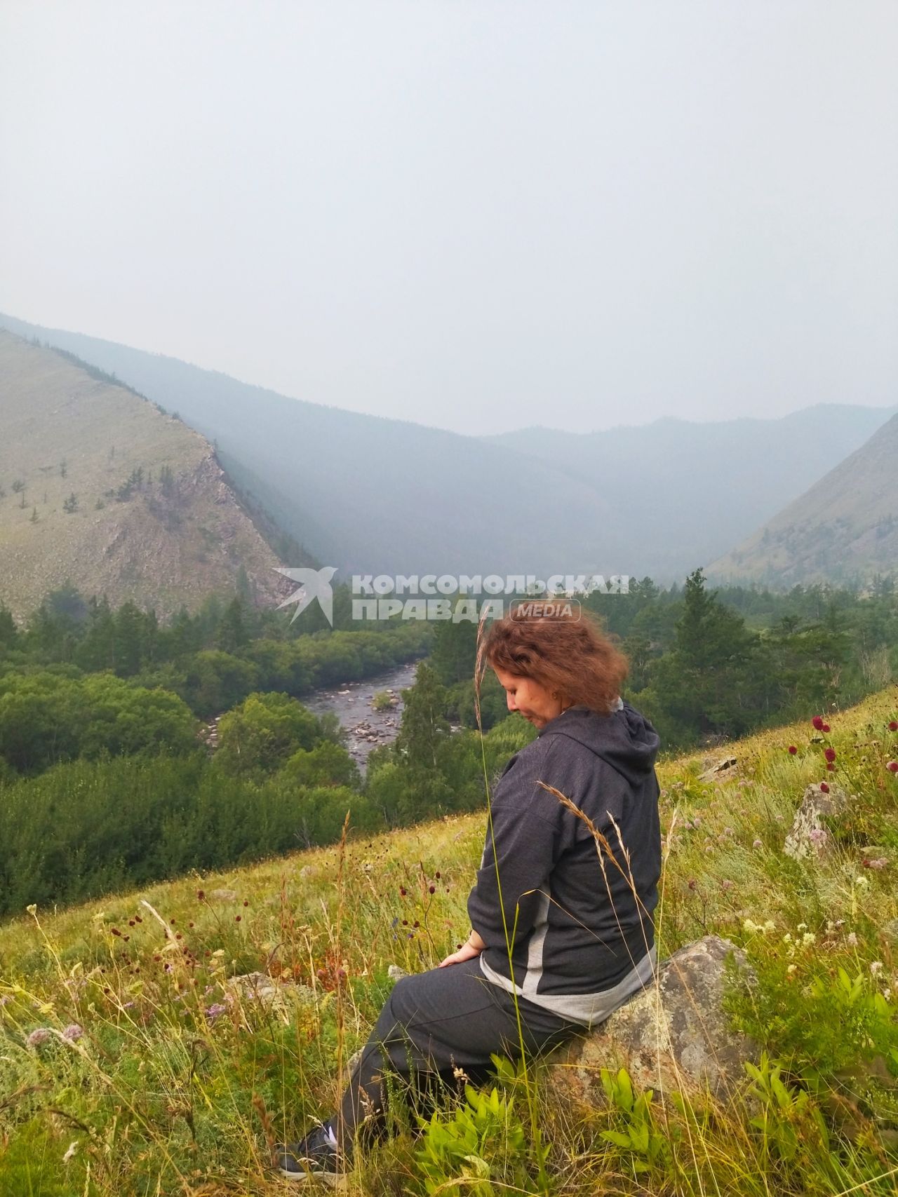 Иркутская область. Девушка сиди на склоне озера Байкал.