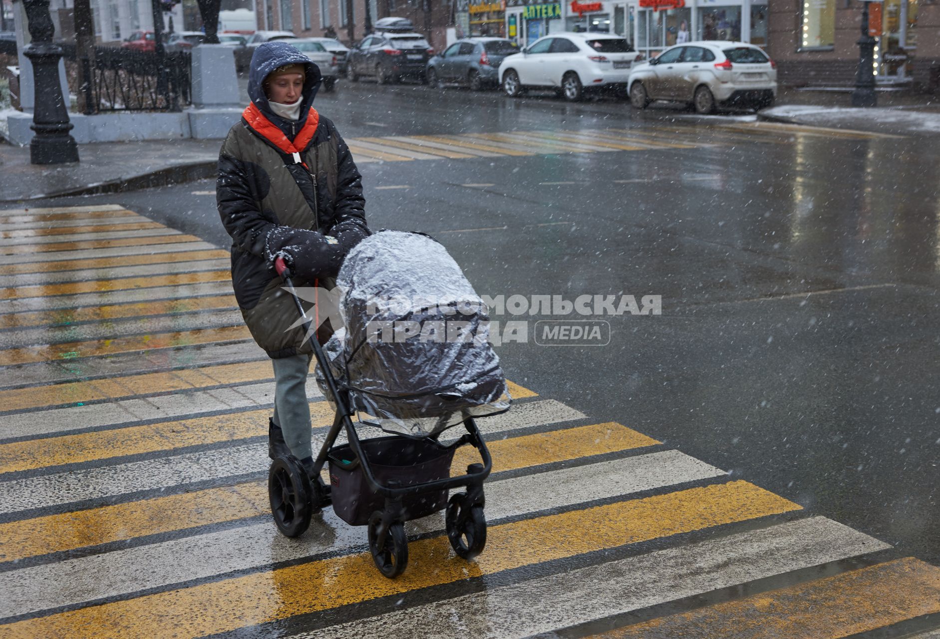 Пермь. Девушка с детской коляской переходит дорогу по пешеходному переходу.